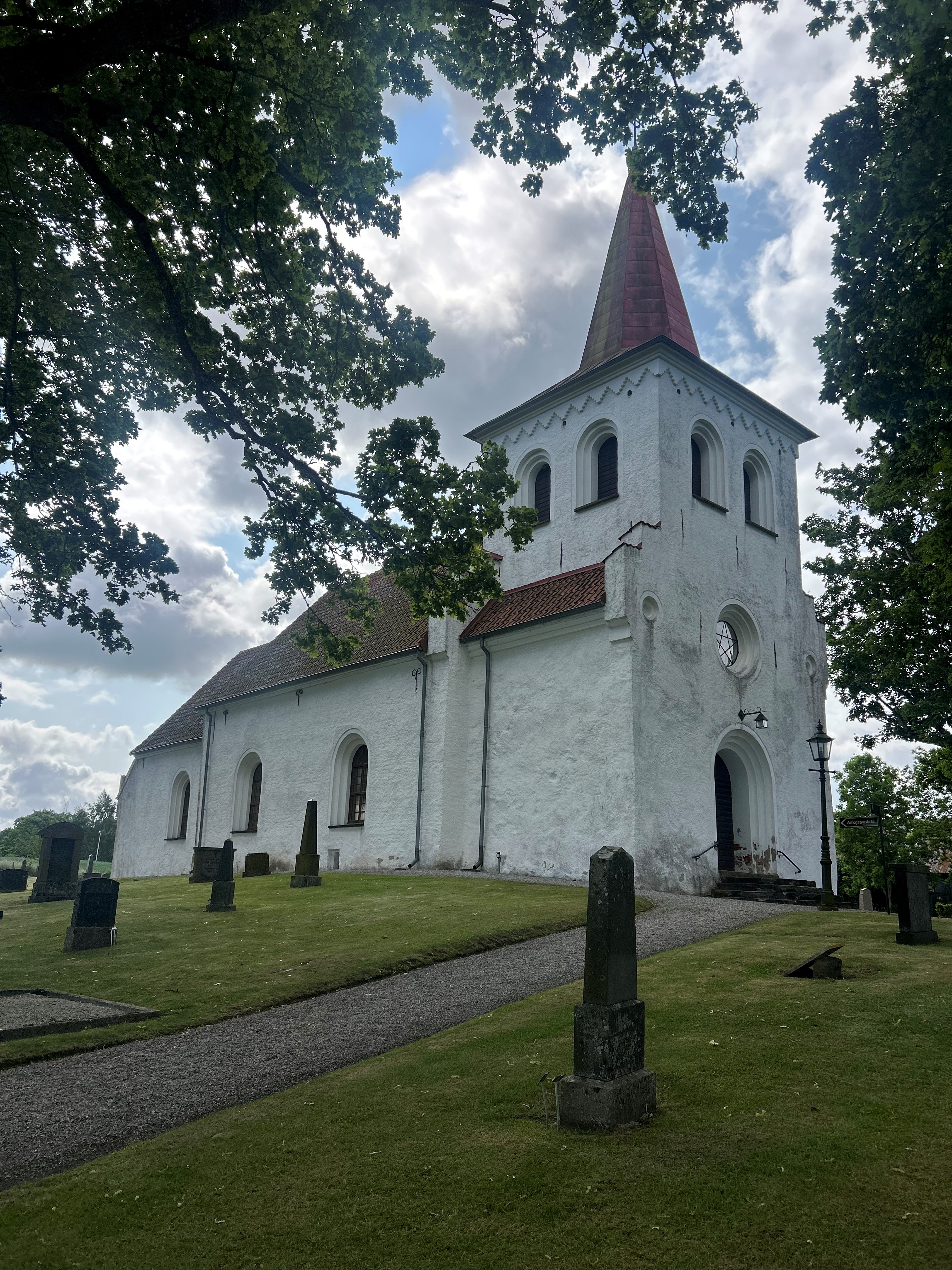 Vit liten kyrkobyggnad med rött tegeltak.