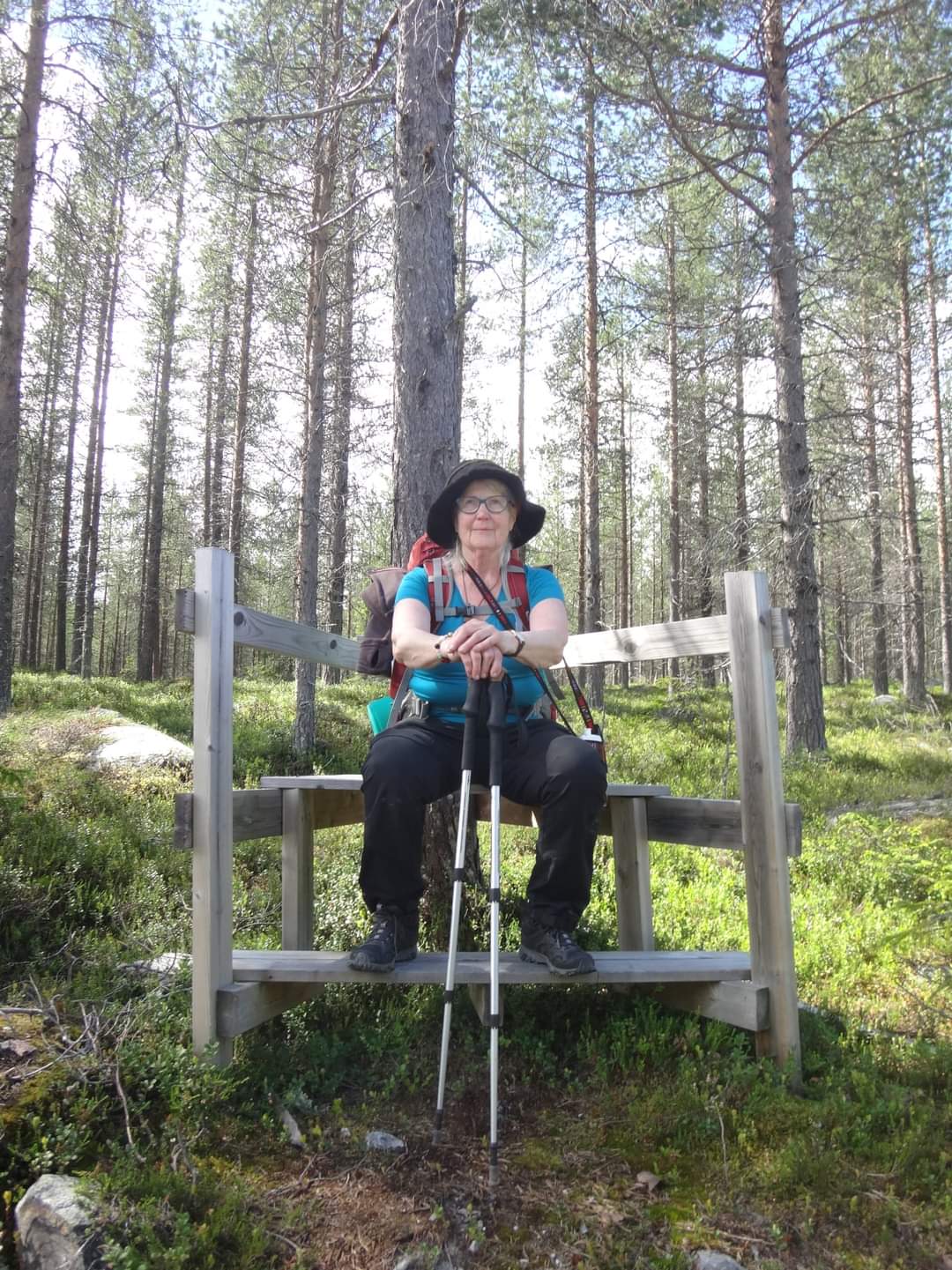 En kvinna i vandringskläder sitter i skogen.