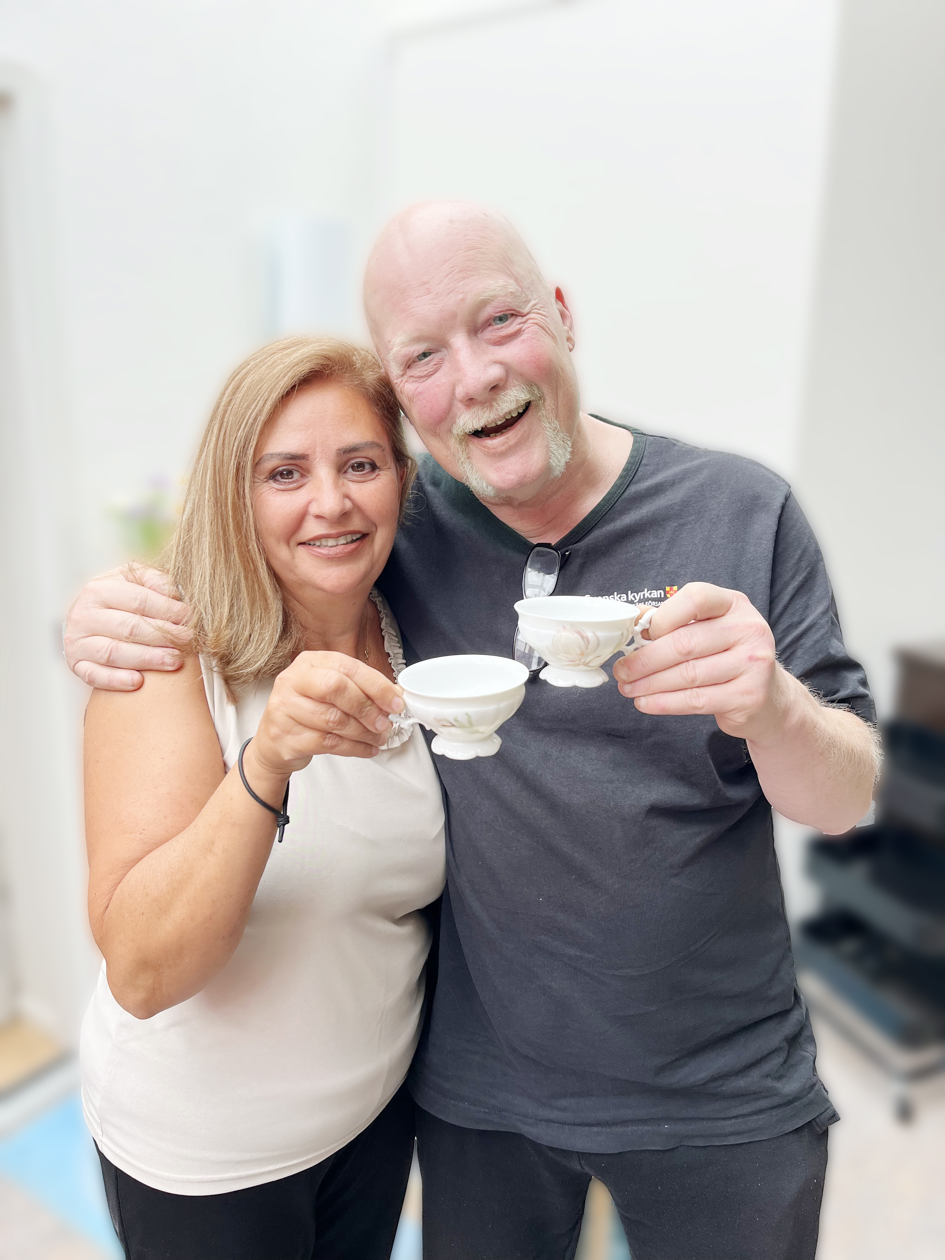 En kvinna och en man som håller i kaffekoppar och ser glada ut.