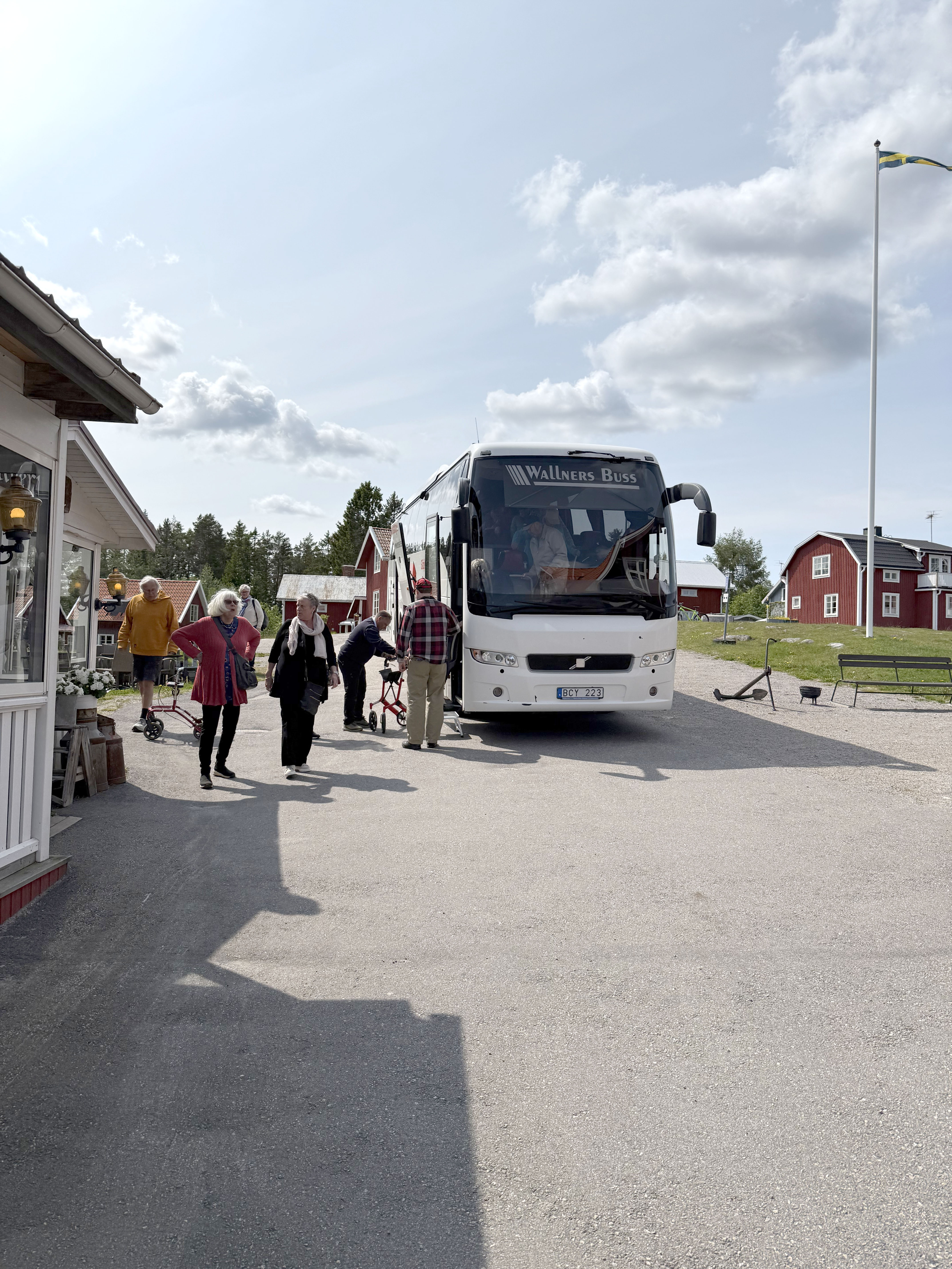 En buss framifrån och några resenärer intill
