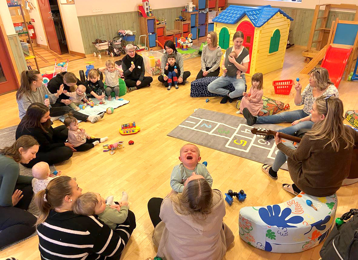 Barn och vuxna sitter i en ring och sjunger.