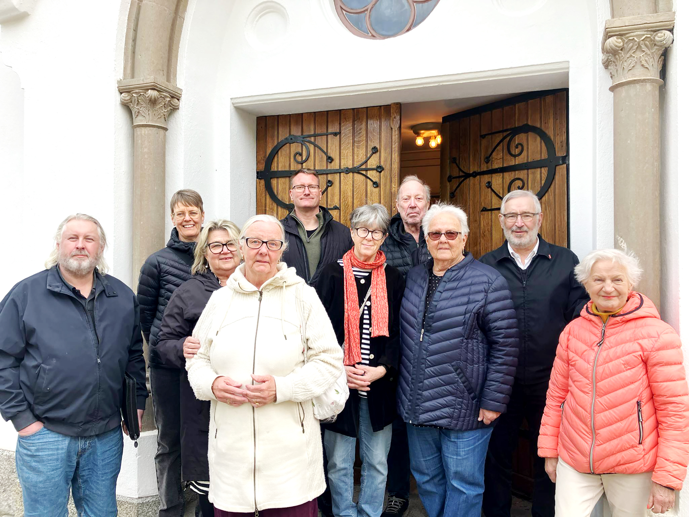 Tio personer står vid kyrkporten.