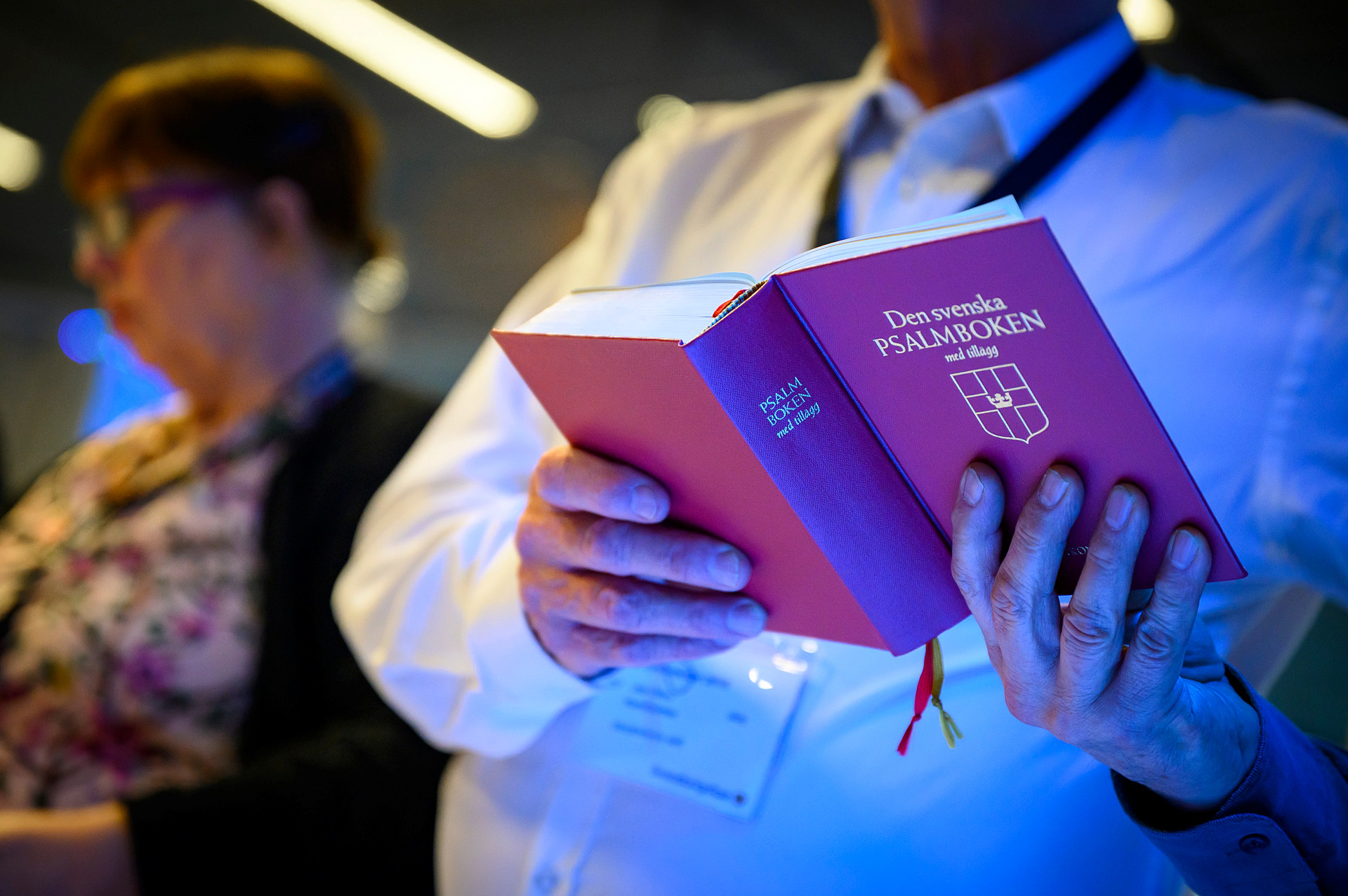Två människor läser i en psalmbok under en mässa eller gudstjänst.