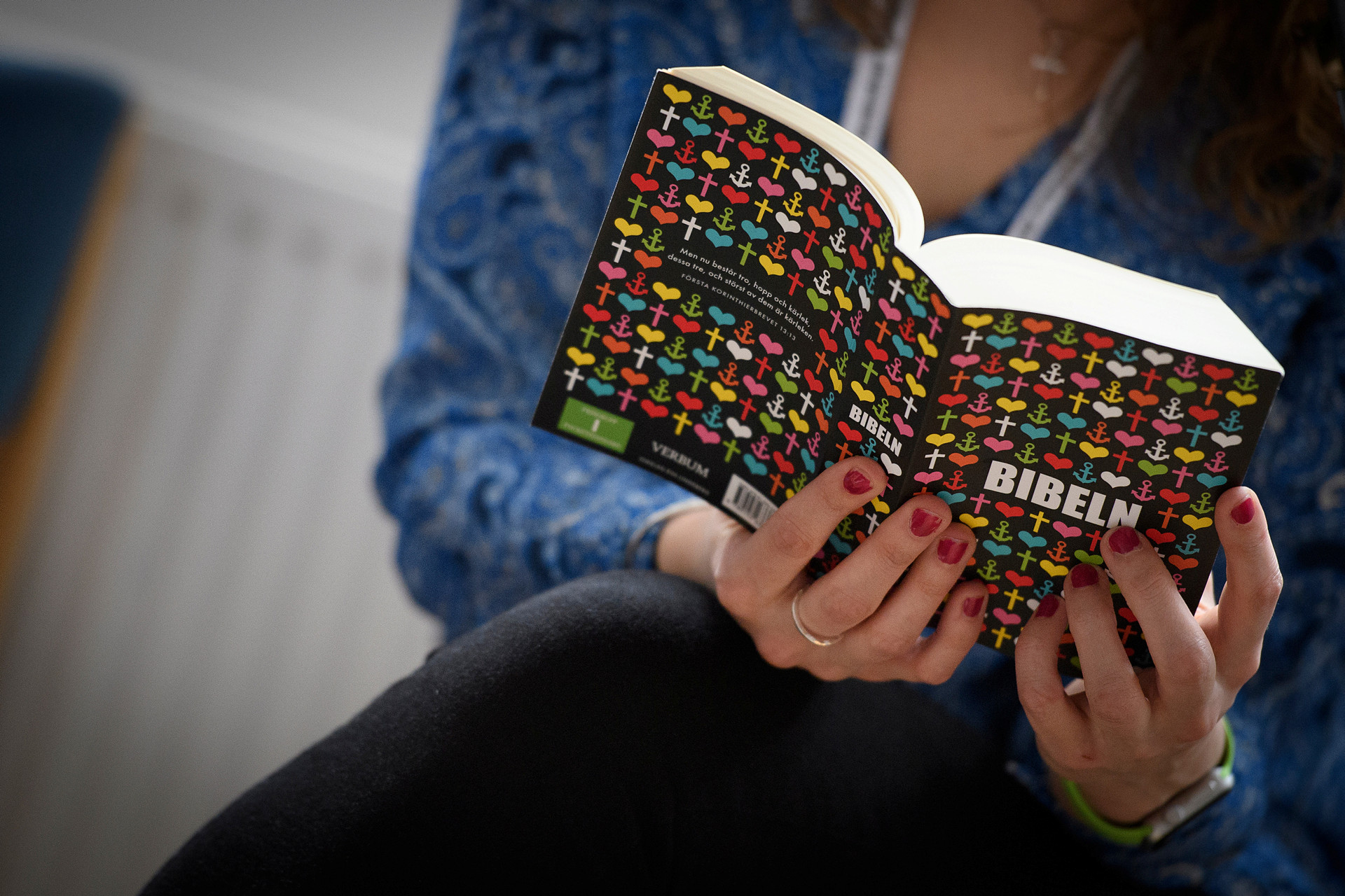 En person håller i en uppslagen bibel av modernare snitt.