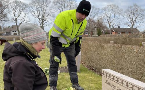 Kyrkogårdsarbetare planterar blommor vid en grav på Östra begravningsplatsen.