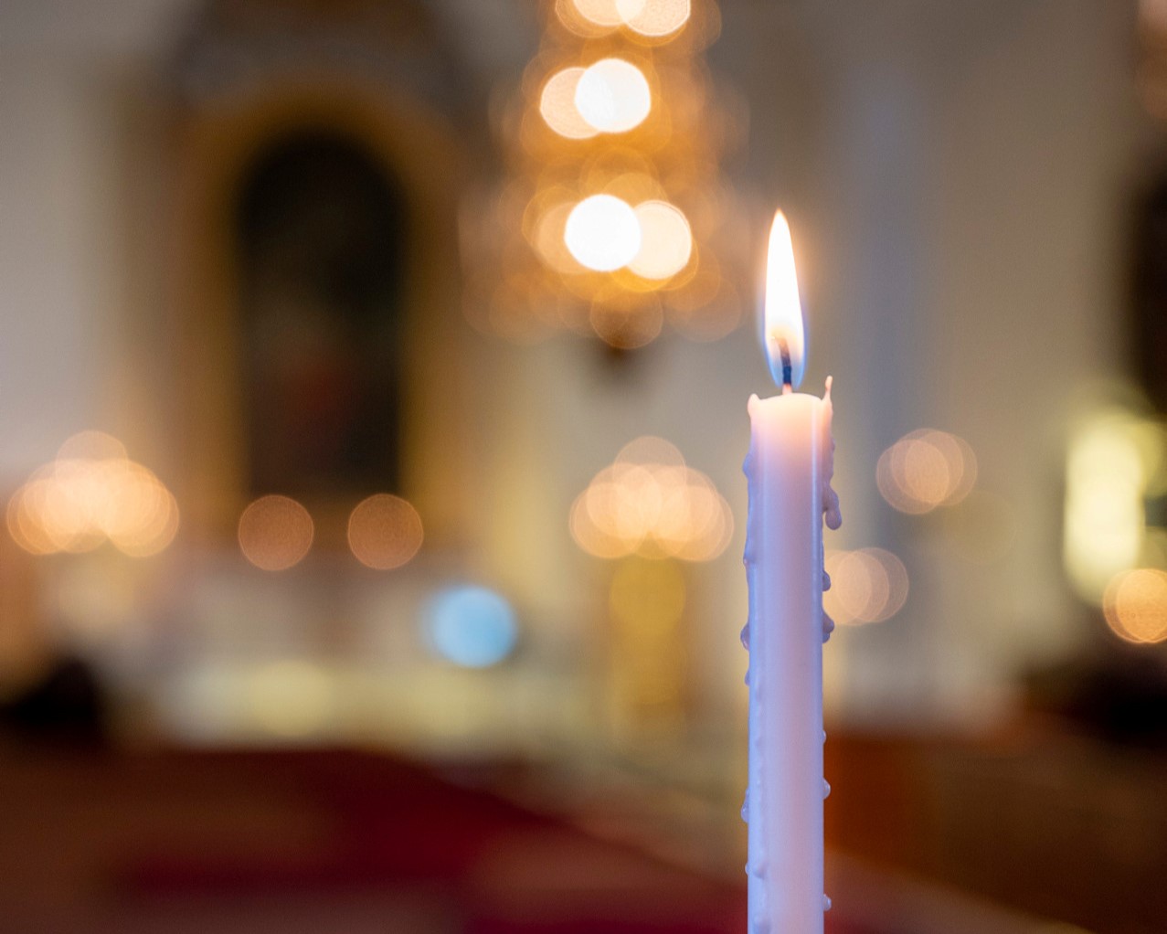 Ett ensamt ljus brinner i ljusbärare i kyrka
