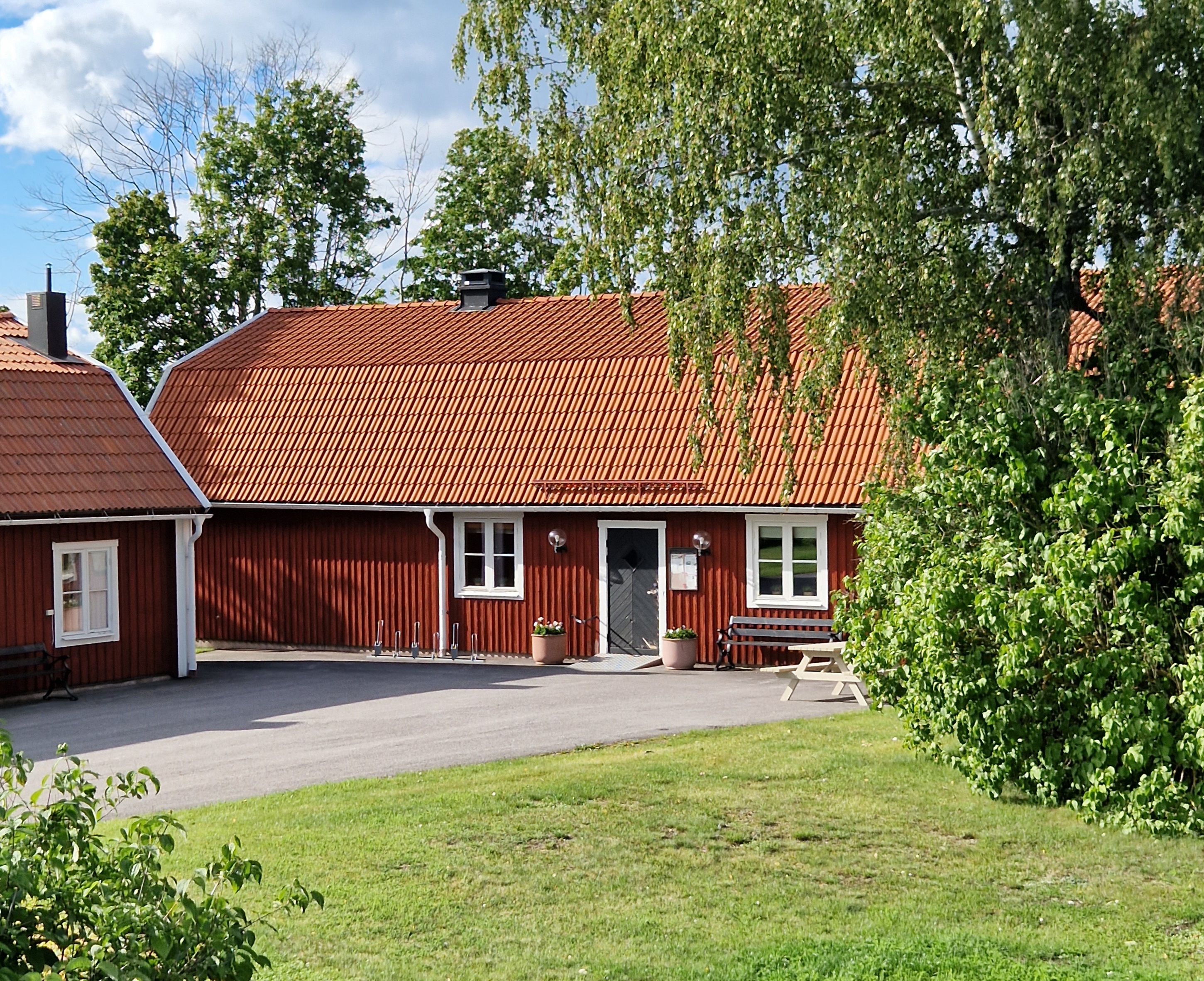 Rött hus med vita knutar och tegeltak i sommargrön miljö