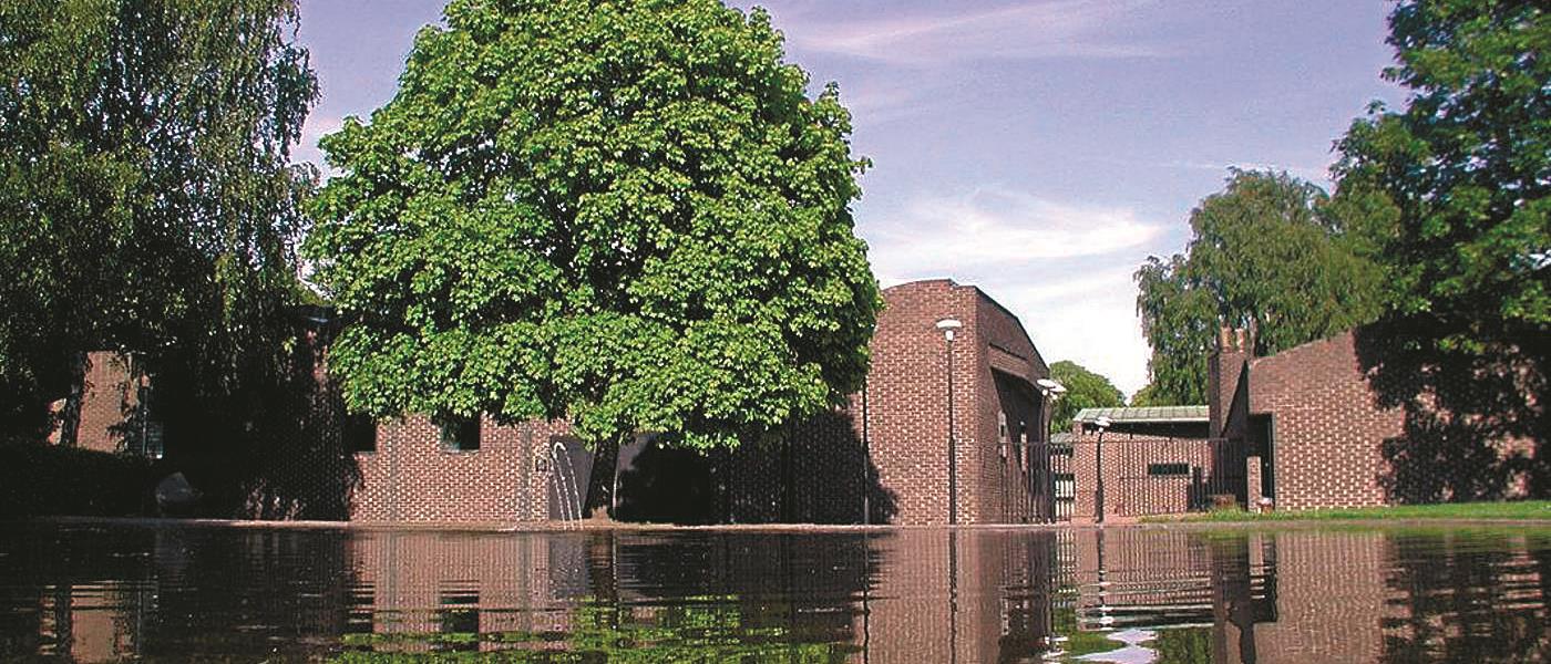 Bilden visar Sankt Petri kyrka i Klippan som speglar sig tillsammans med träd i vattnet