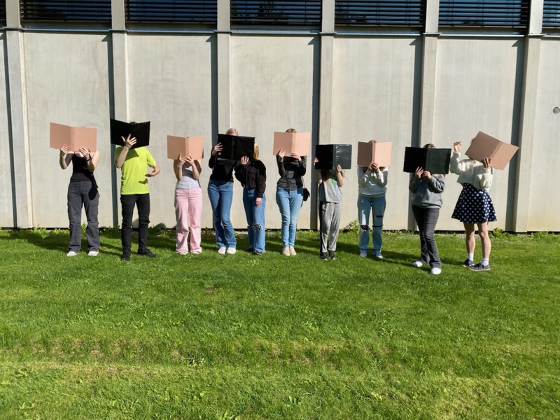 Bilden visar ungdom med notpärmar framför ansiktet