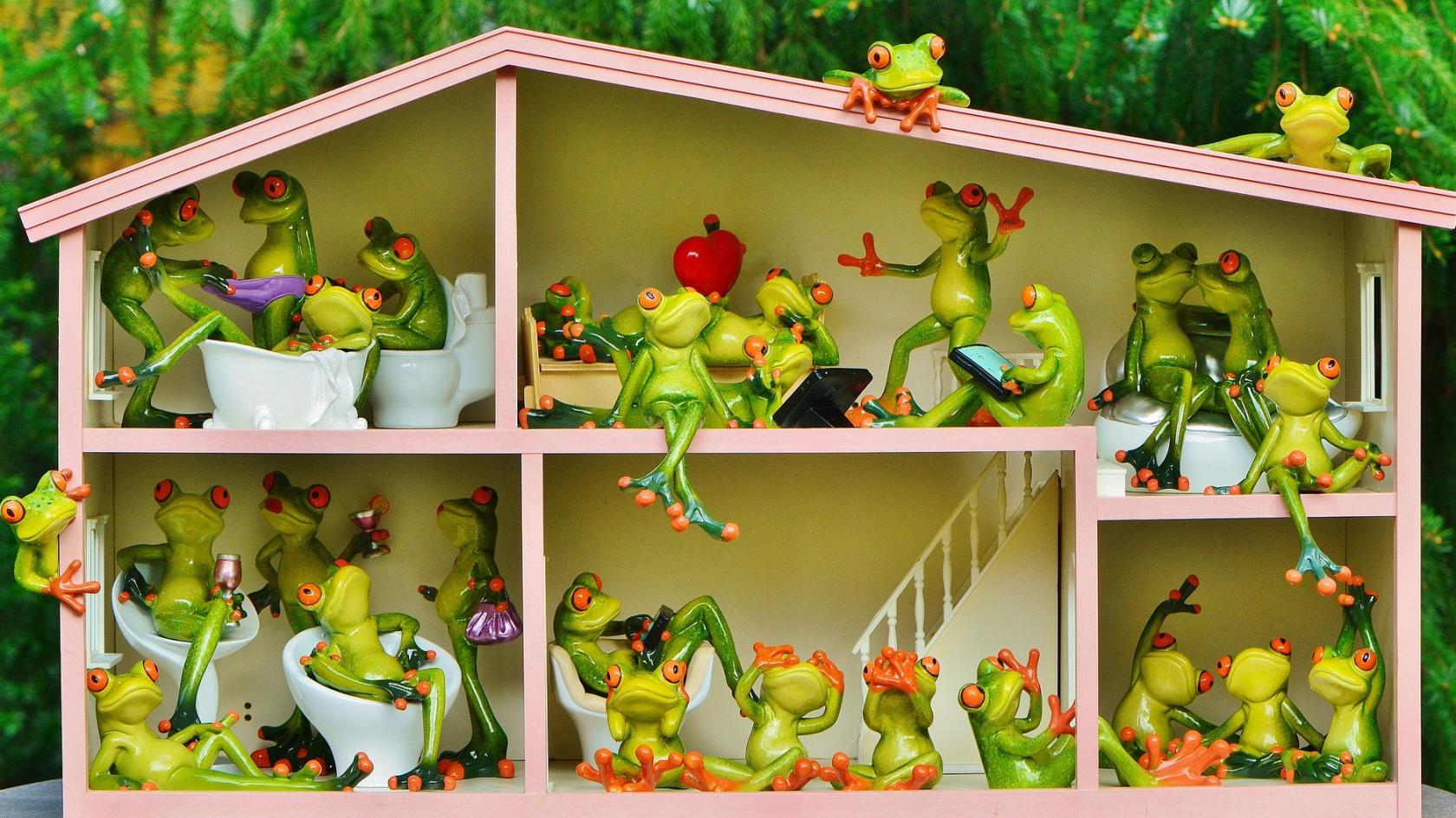 Bilden föreställer ett dockhus som är bebott med många grodor som håller på med olika saker