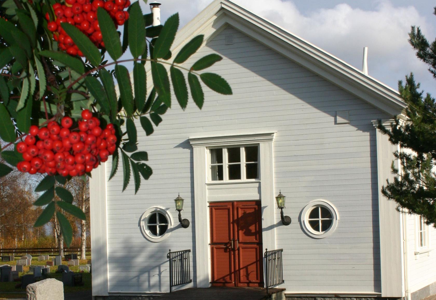 S:ta Cecilia kapell på Burträsk begravningsplats betraktad med en klase röda rönnbär i förgrunden