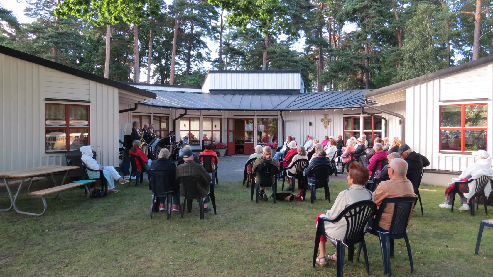 Folk som sitter och lyssnar på levande musikutomhus