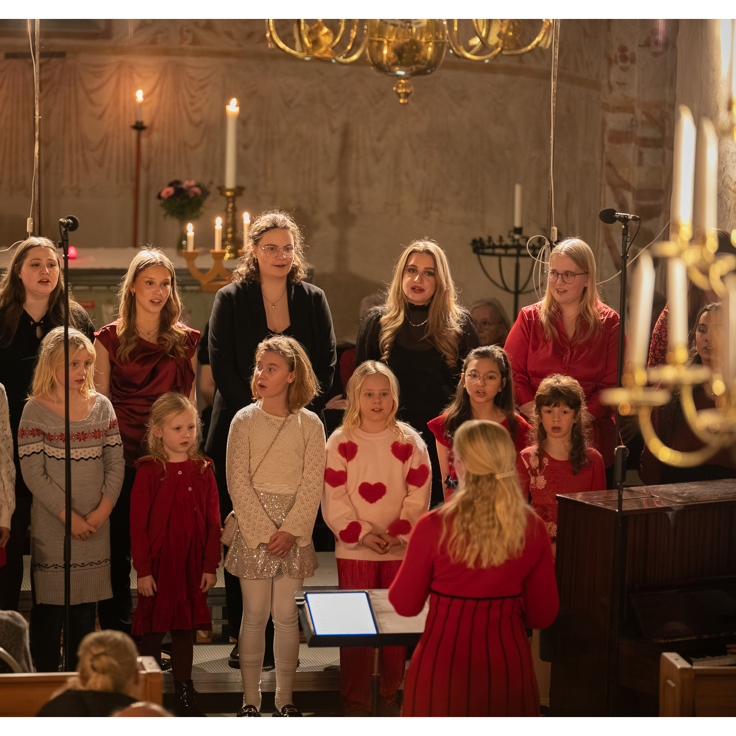 Barn och ungdomar står i den medeltida kyrkans kor och sjunger.