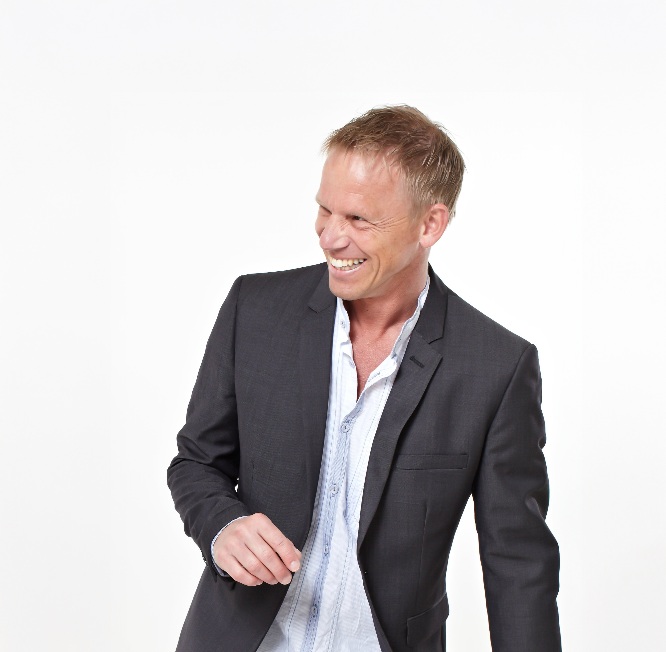 Leende man med mörk kavaj och uppknäppt skjorta.