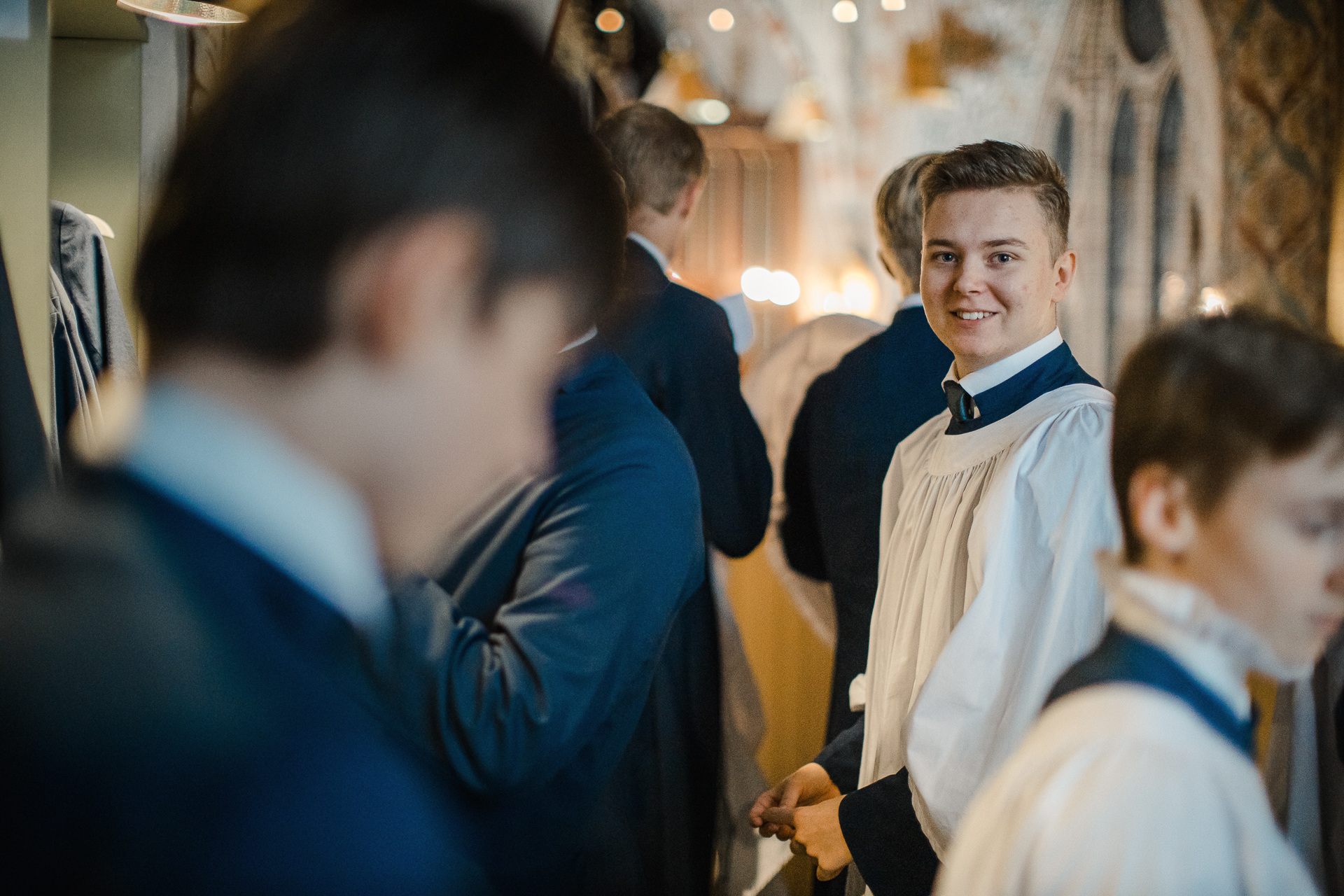 Pojkar i blå och vita körkåpor förbereder sig för att sjunga i en gudstjänst.