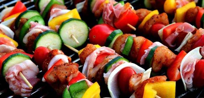 Grillspett med gurka, paprika och kött ligger tätt på ett grillgaller.