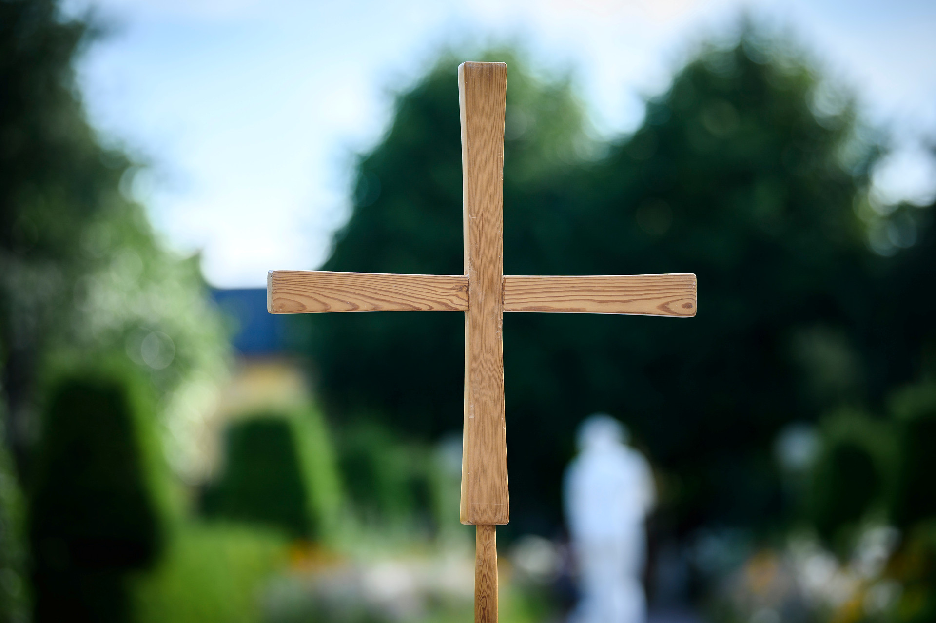 Närbild tagen utomhus på ett träkors med träd i bakgrunden.