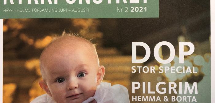 Baby i dopdräkt. Kyrkfönstret i vita bokstäver mot grön bakgrund.