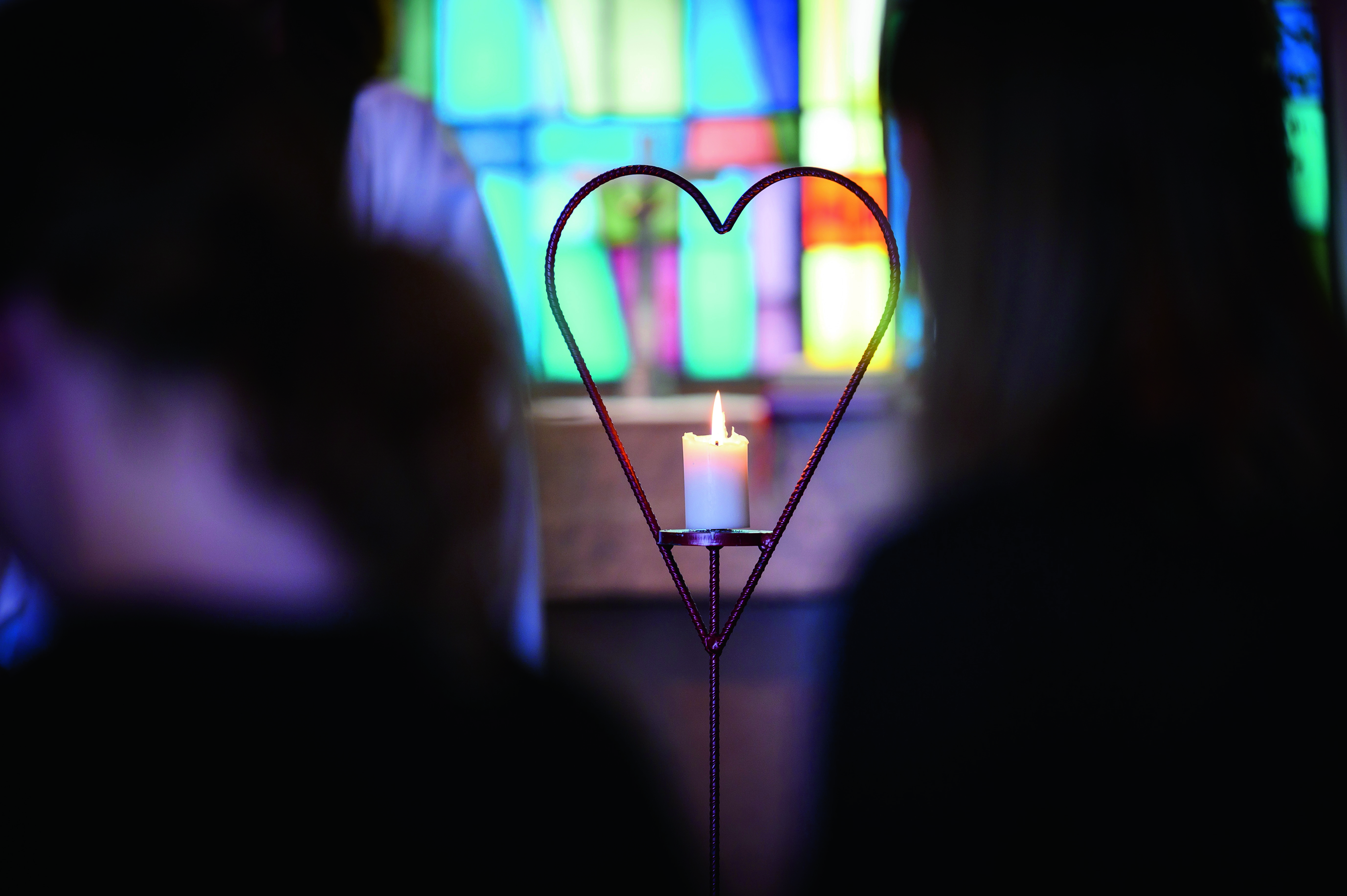 Ett hjärta med ett brinnande ljus i. Människor skymtar.