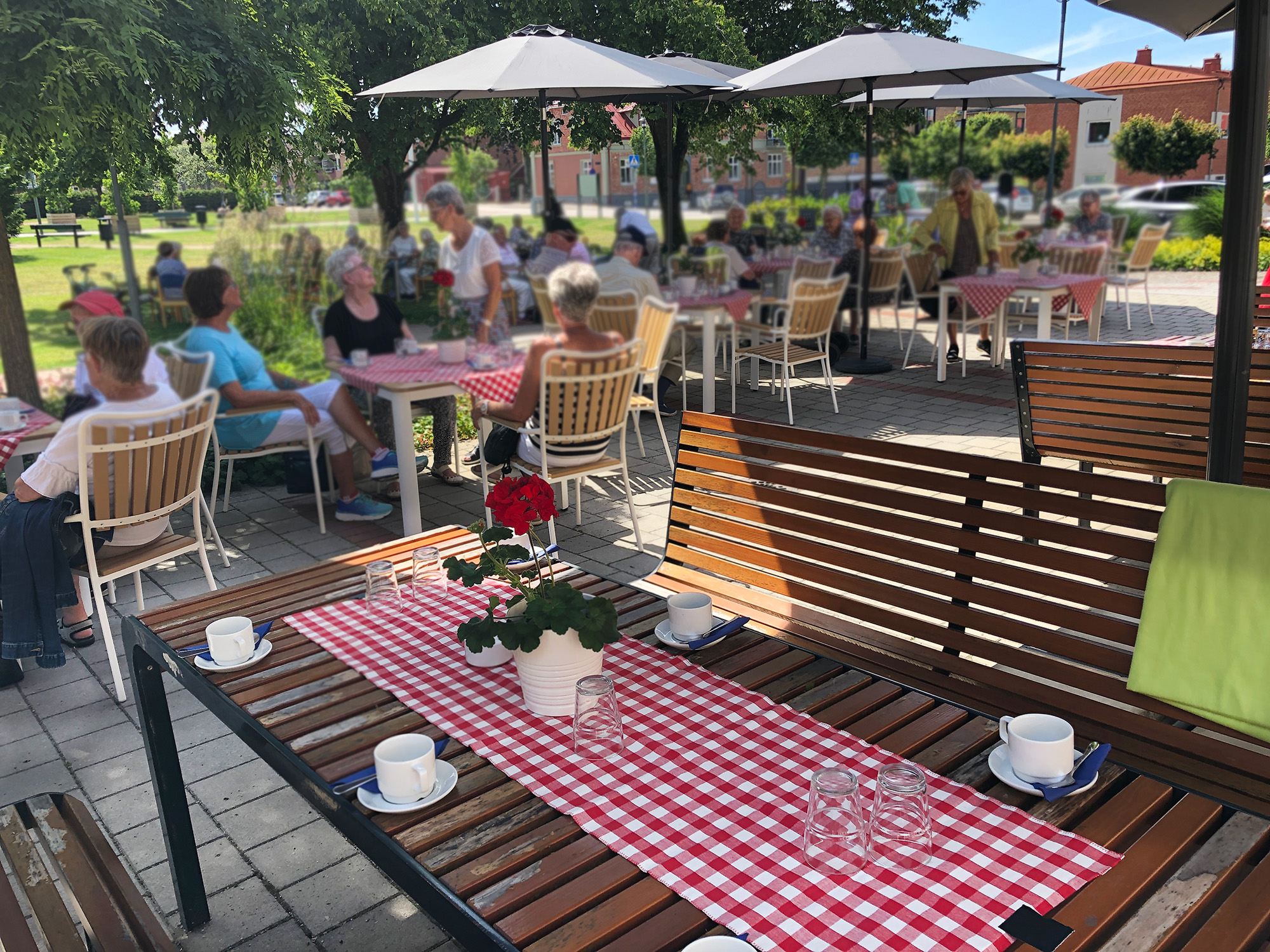 Dukat med rödvitrutiga dukar till sommarcafé utanför Hässleholms församlingshus.