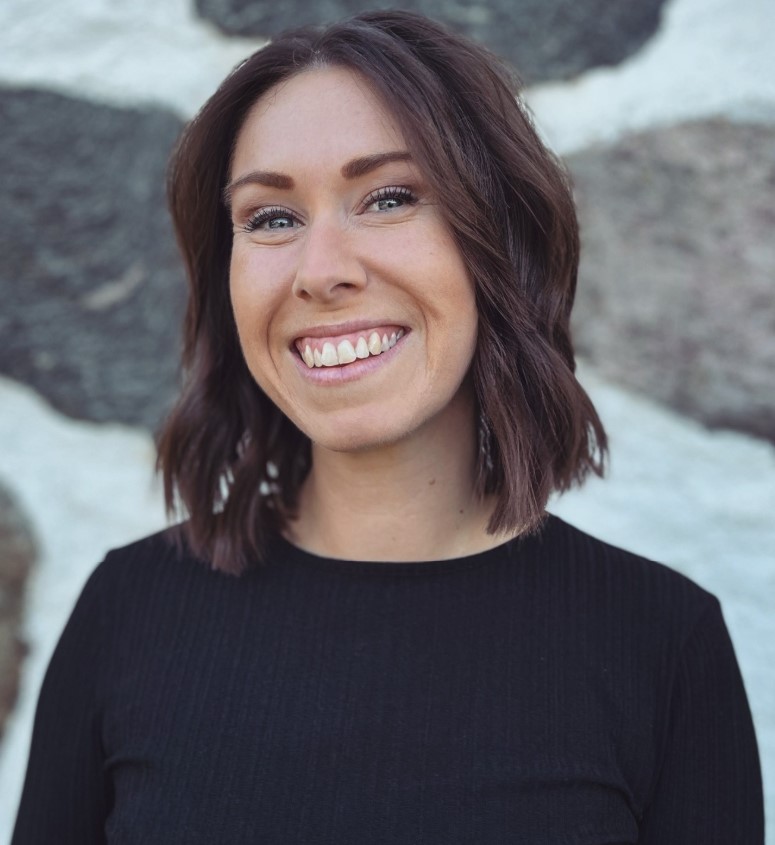 Leende kvinna med halvlångt mörkt hår och mörk tröja.