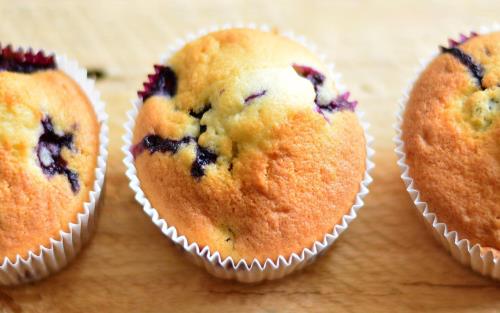 Tre ljust gräddade muffins med blåbär i.