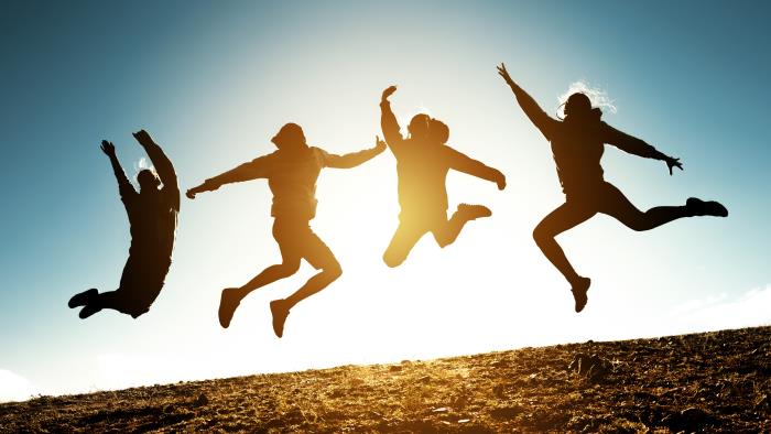 Tonåringar som hoppar, de syns enbart som siluetter mot en ljus himmel.