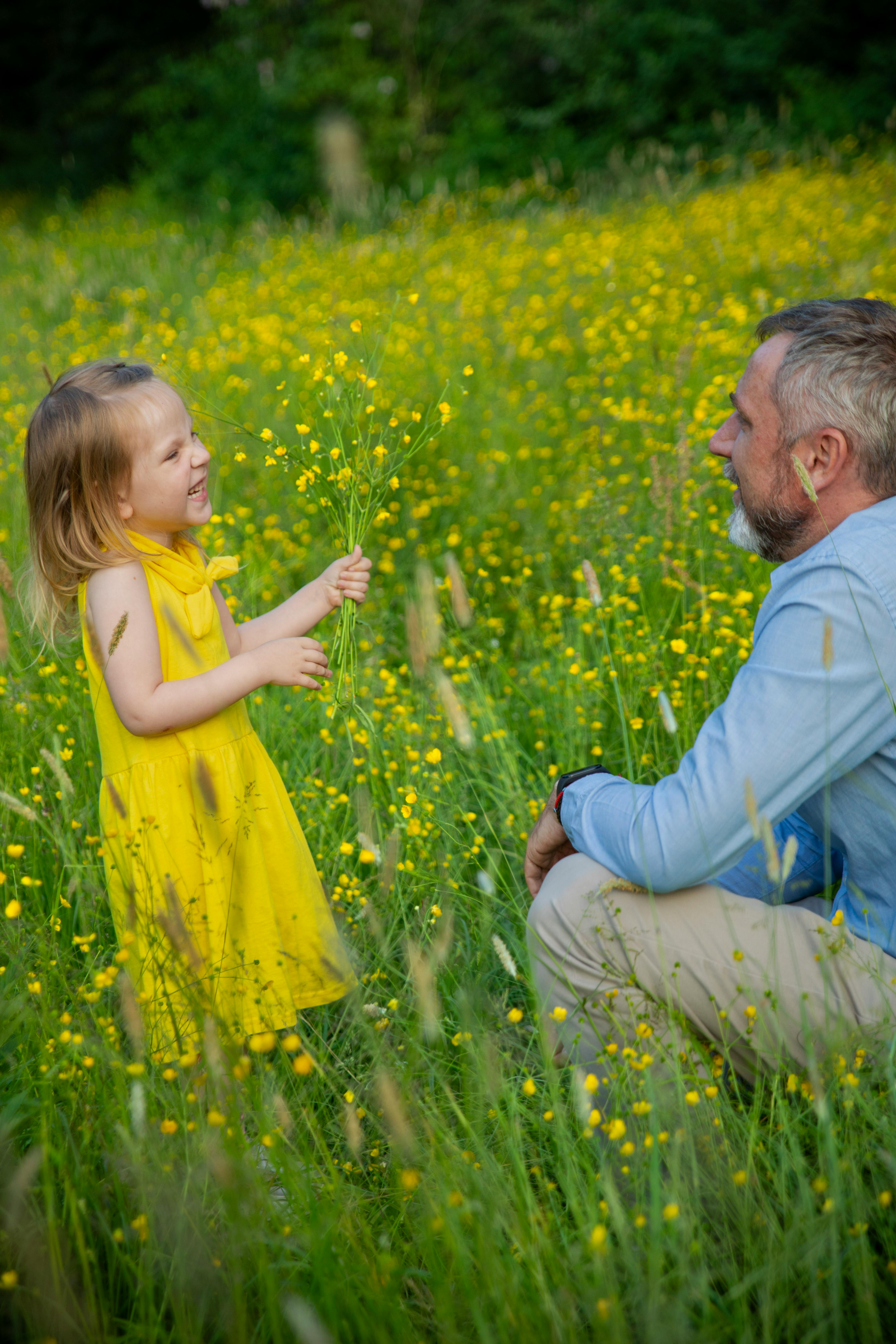 En flicka i gul klänning med en bukett blommor i handen