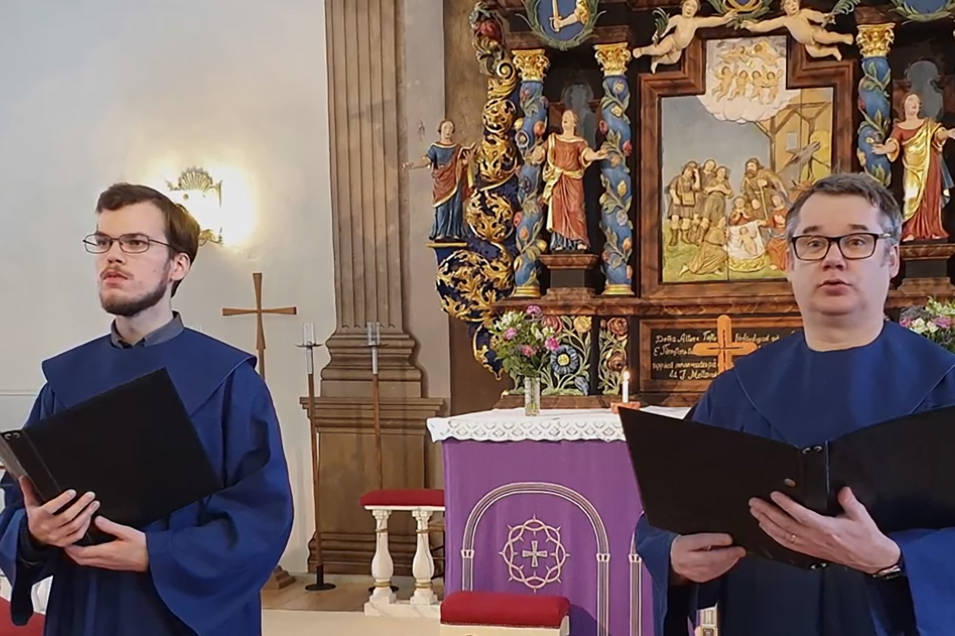 Två män i blåa kappor framför altartavlan i Bollebygds kyrka