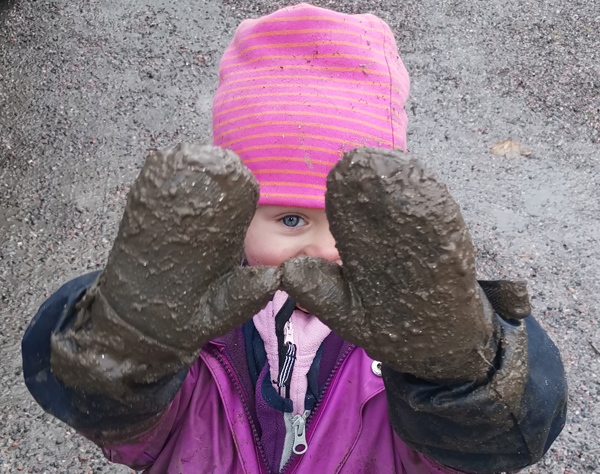 Barn med rosa mössa och smutsiga vantar