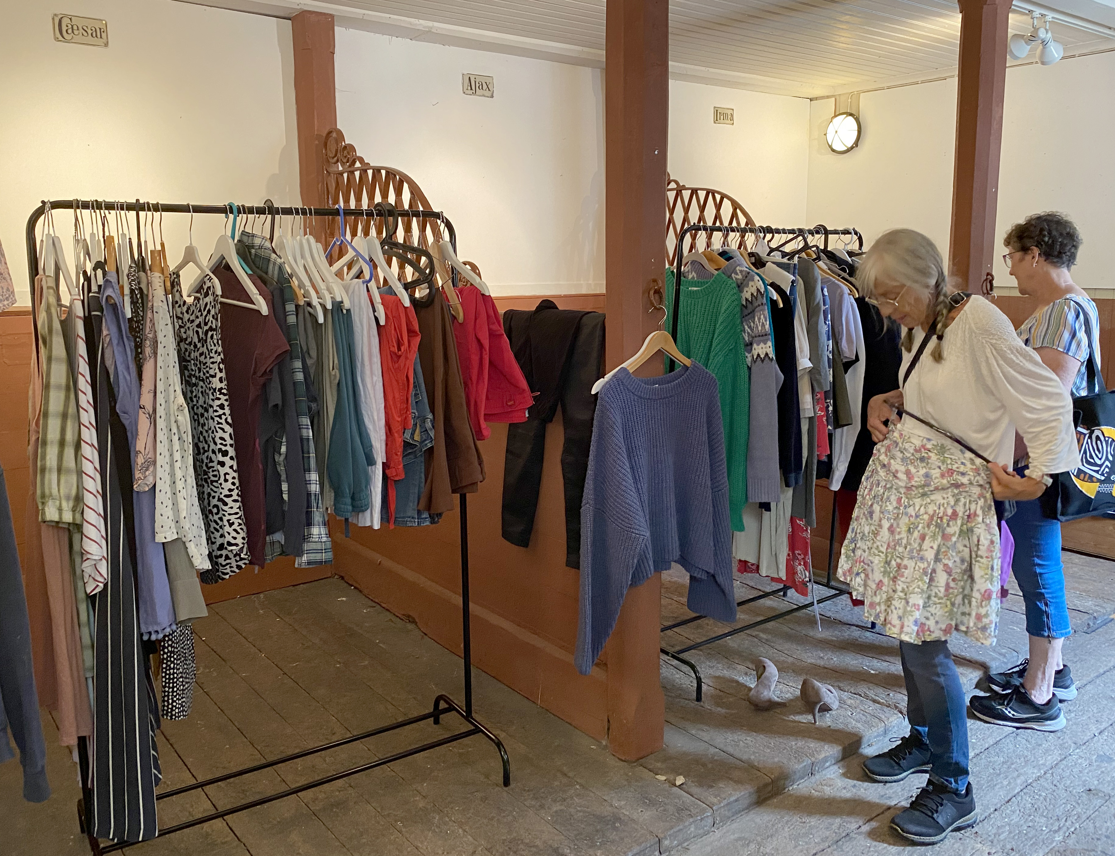 Två kvinnor tittar på kläder på Loppis i Stallet