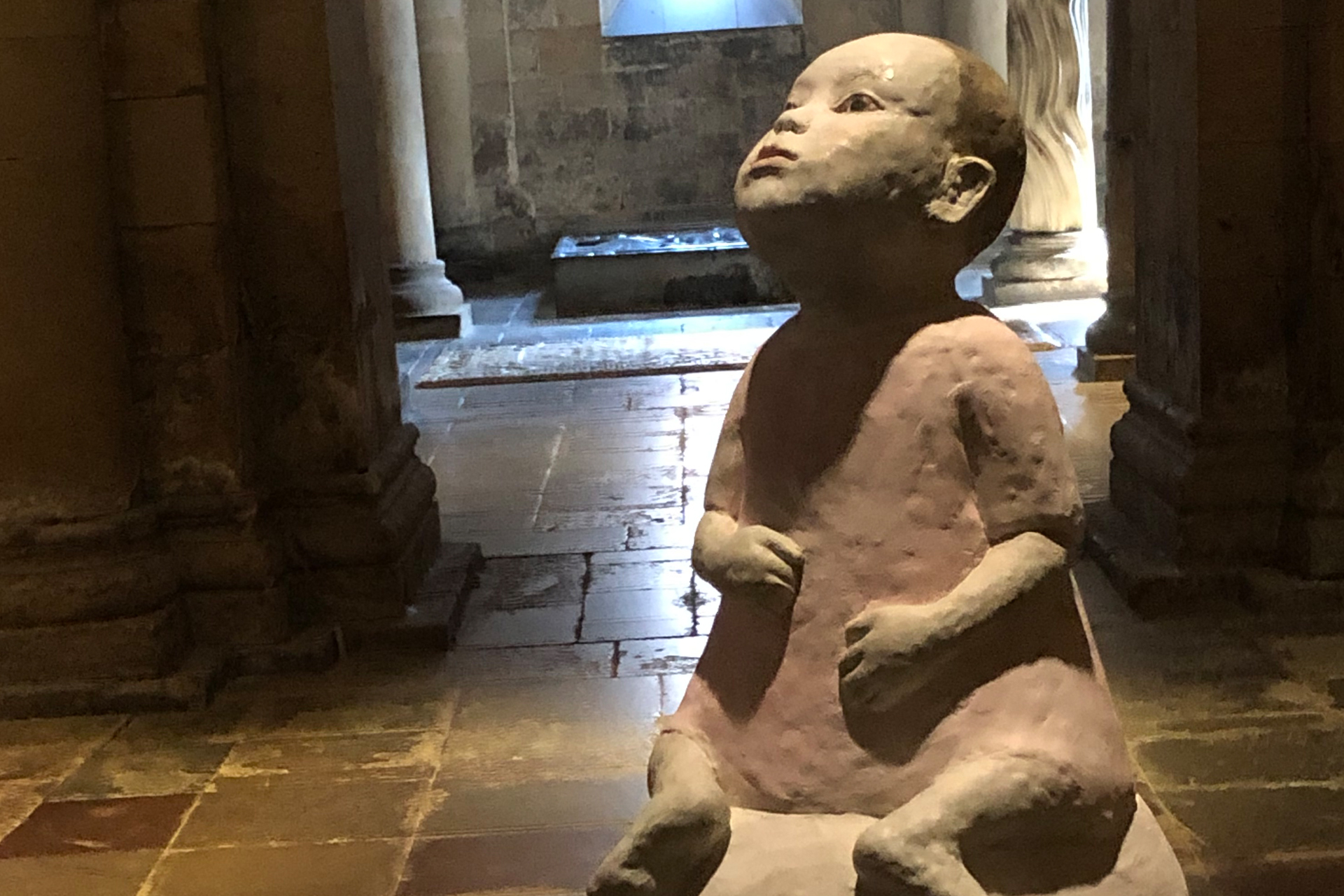 En lerfigur i form av ett barn som tittar uppåt.