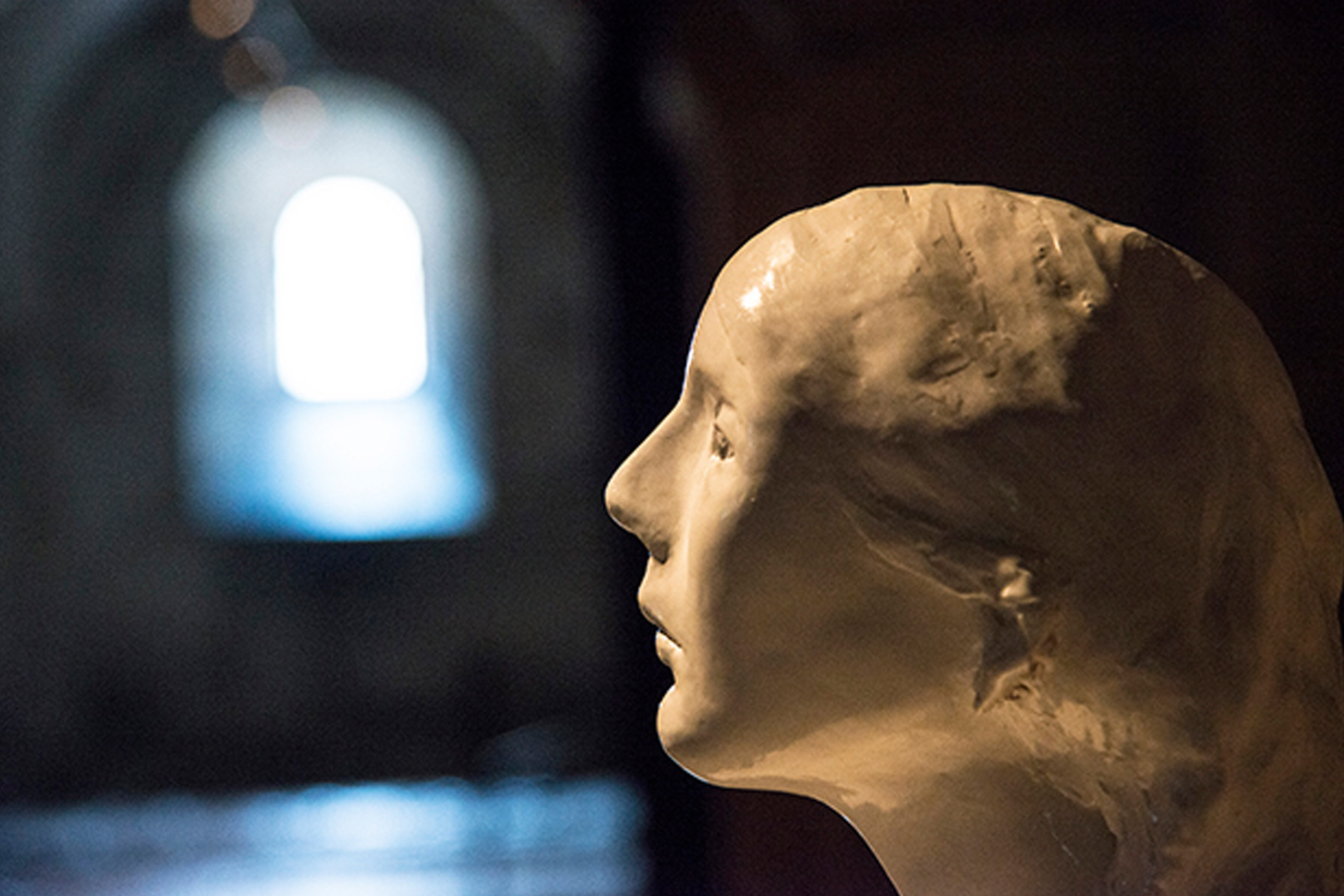 Ett ansikte i profil i motljus från ljusinsläppet i kryptan.