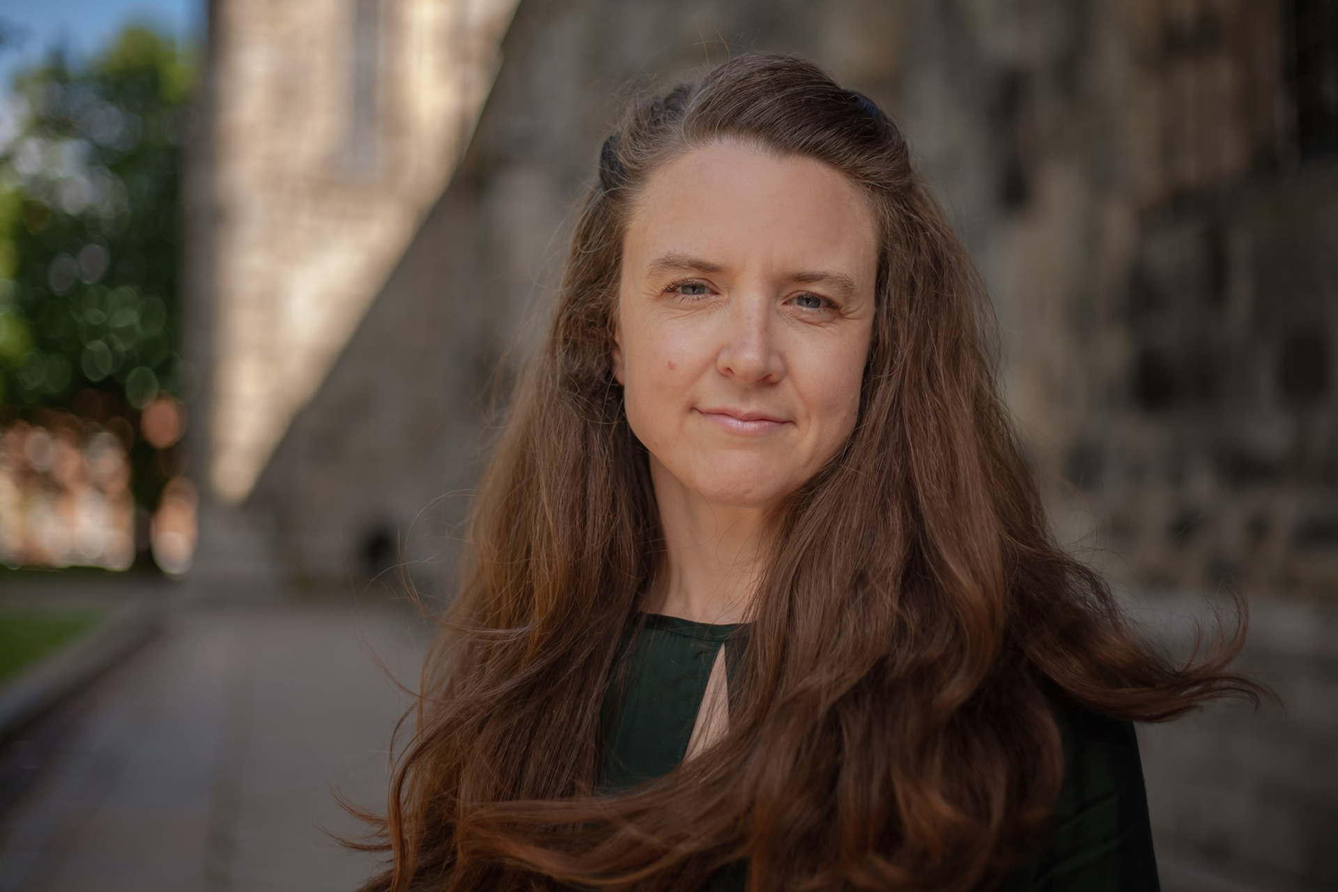 Kvinna med långt brunt hår och svart blus står utanför Lunds domkyrka.