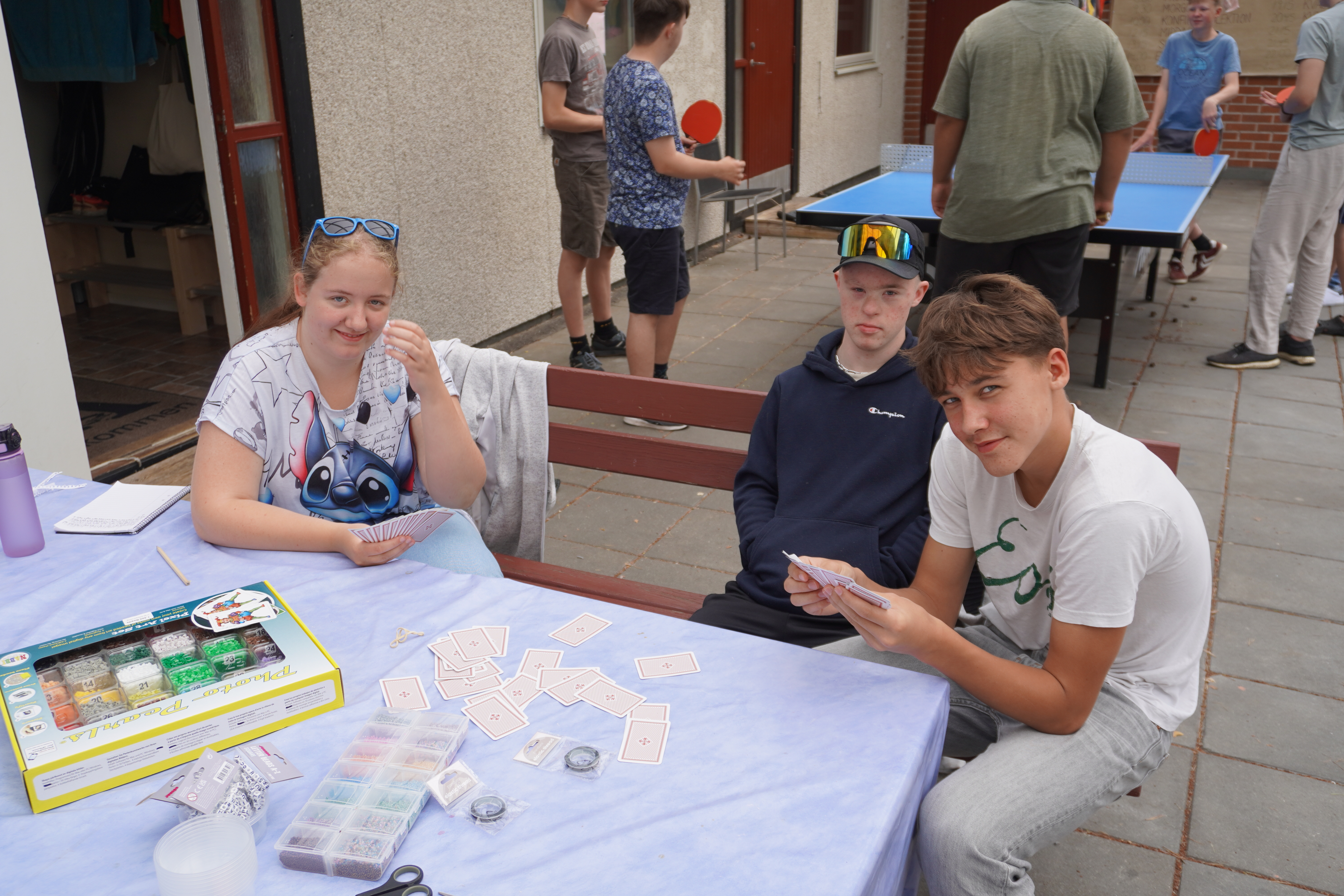 Tre konfirmander sitter vid ett bord och spelar kort.