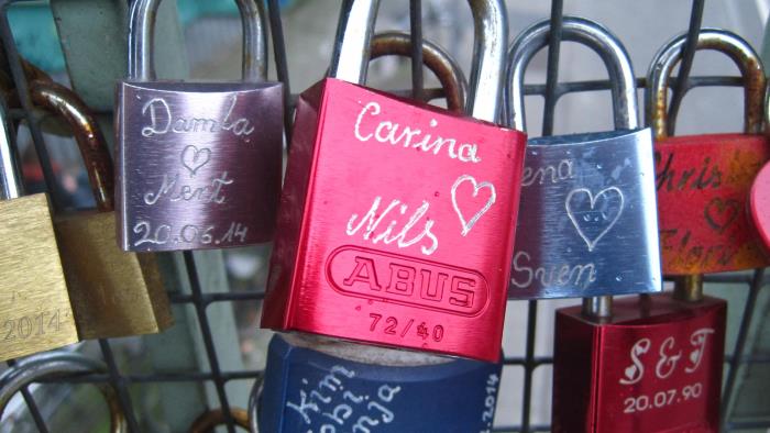 Hänglås med kärlekspars namn på hänger på ett stängsel
