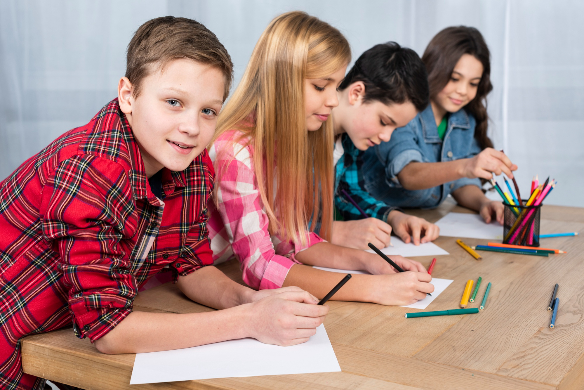 Fyra barn vid ett bord med papper och pennor