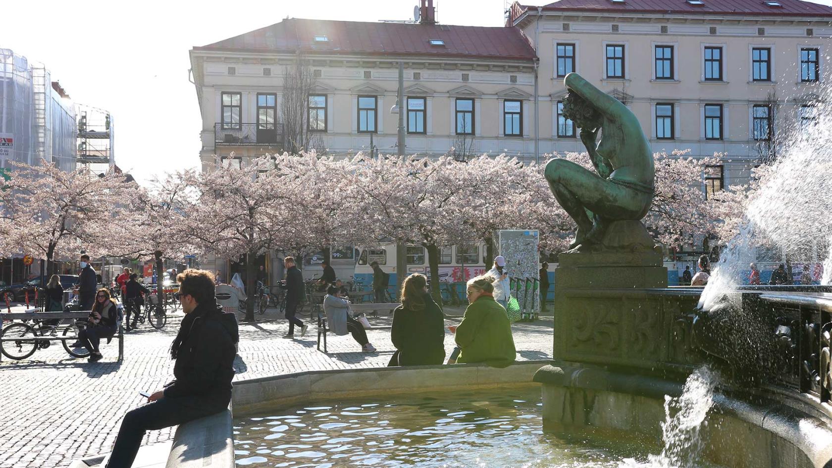 Några personer sitter på kanten på Järntorgets fontän.