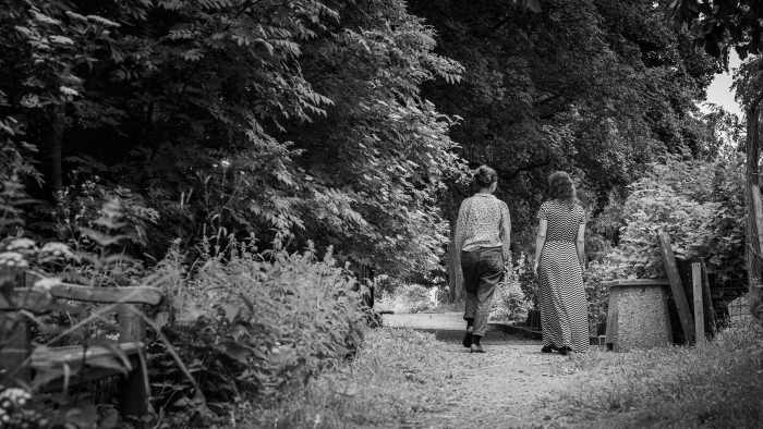 Två personer går längs en stig och pratar med varandra.