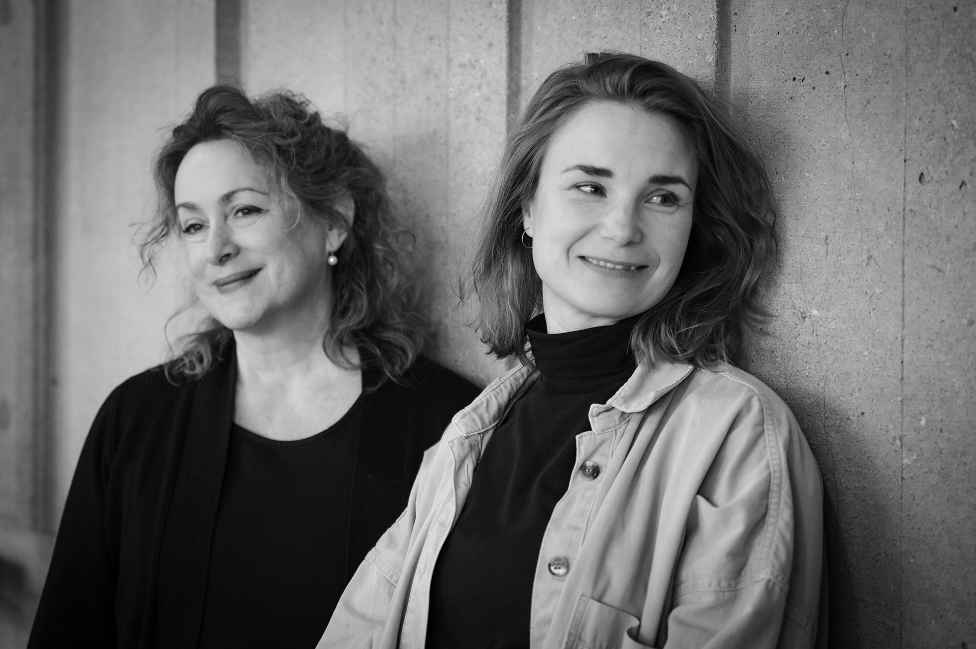 Svartvit bild Lotti Sharif och Karolina Gustavsson mot en betongfasad..