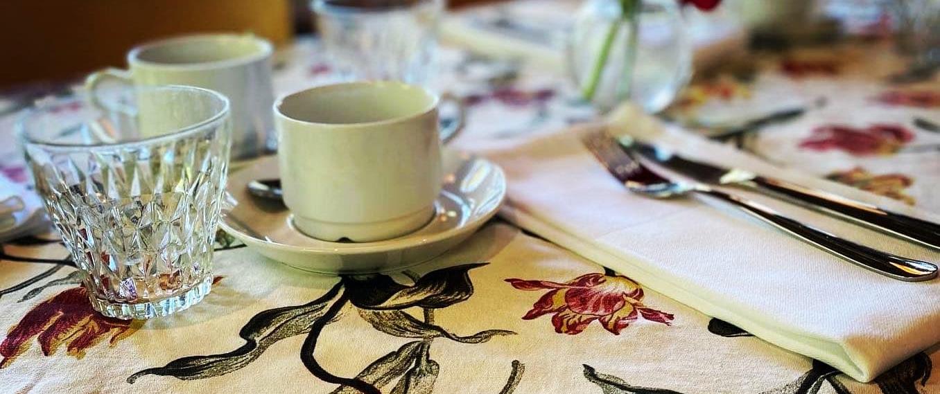 Kaffekopp på fat på en blommig duk