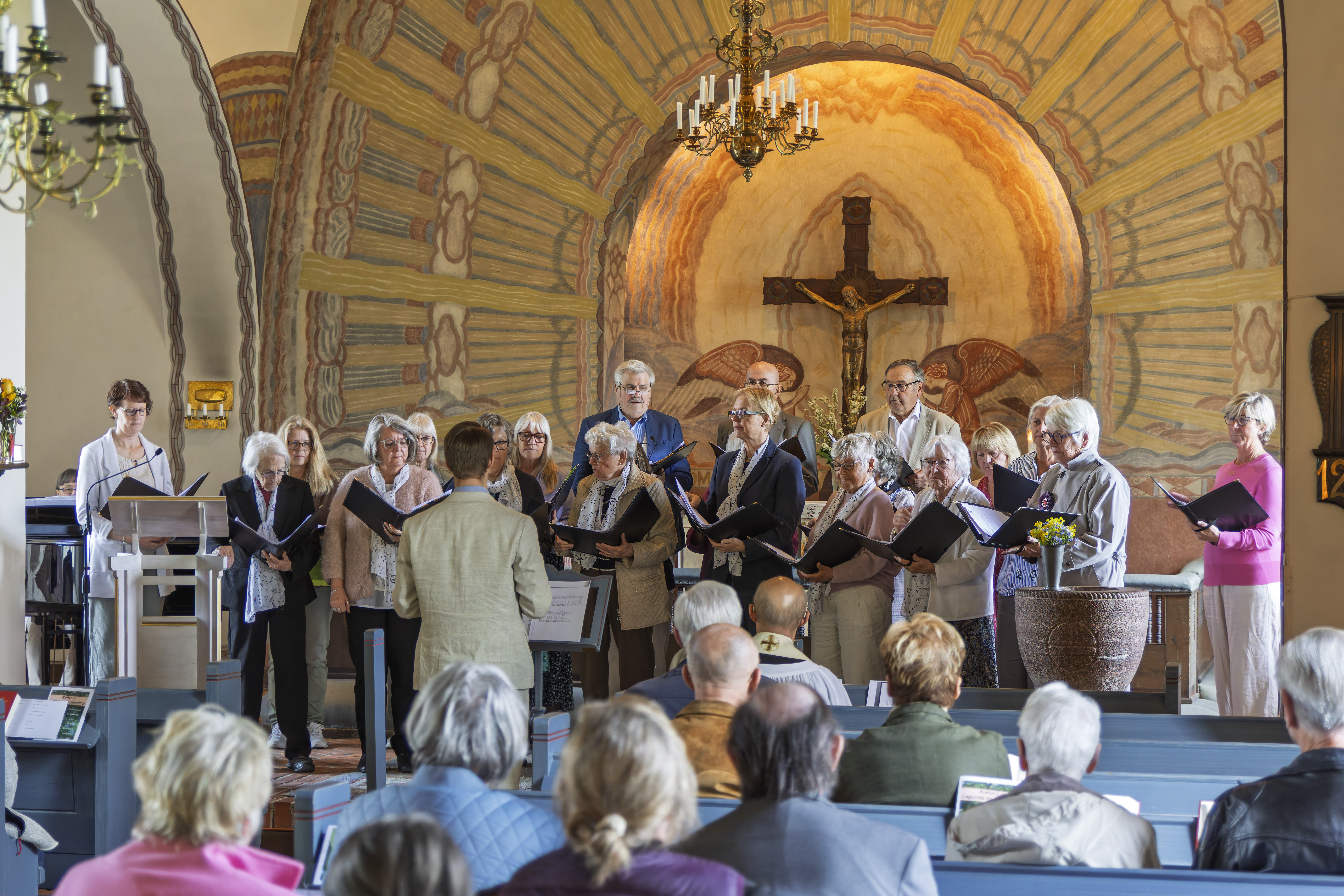 En kör på ett tjugotal personer uppträder framme vid altaret i Giresta kyrka