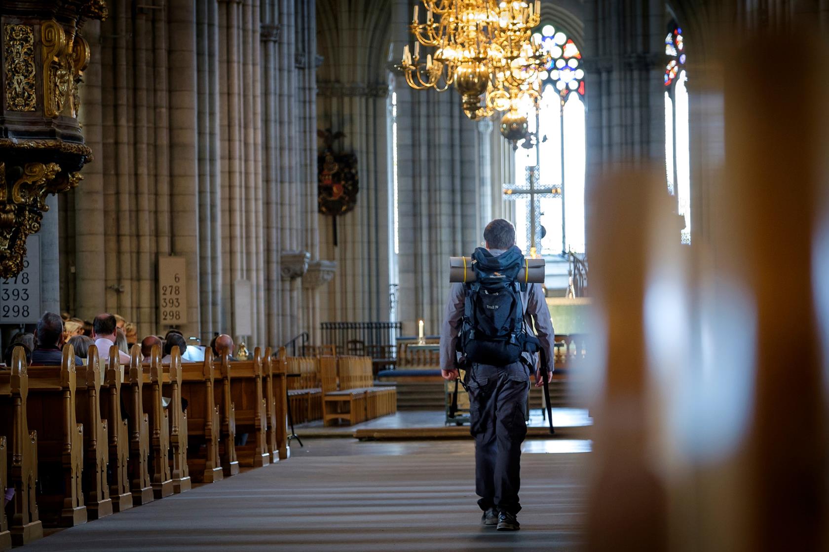 En man med ryggsäck går in i en kyrka