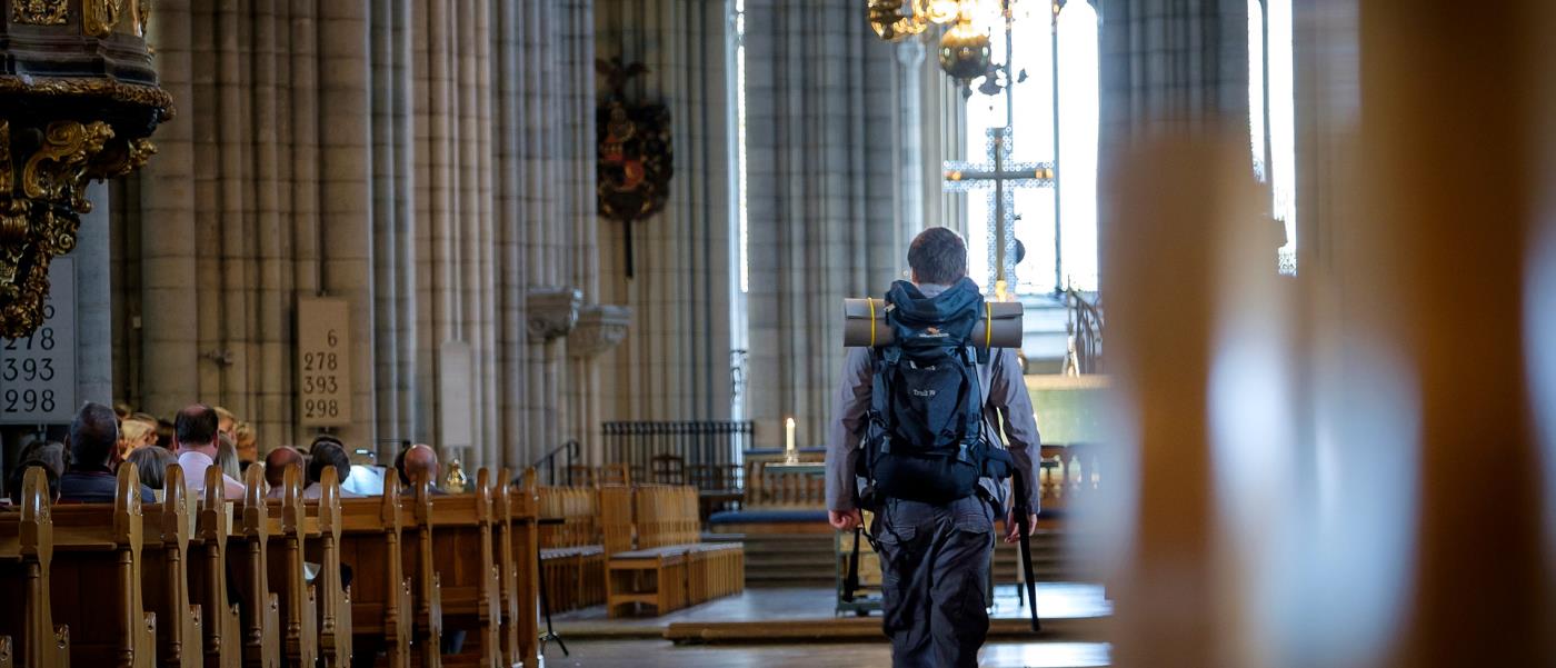 En man med ryggsäck går in i en kyrka