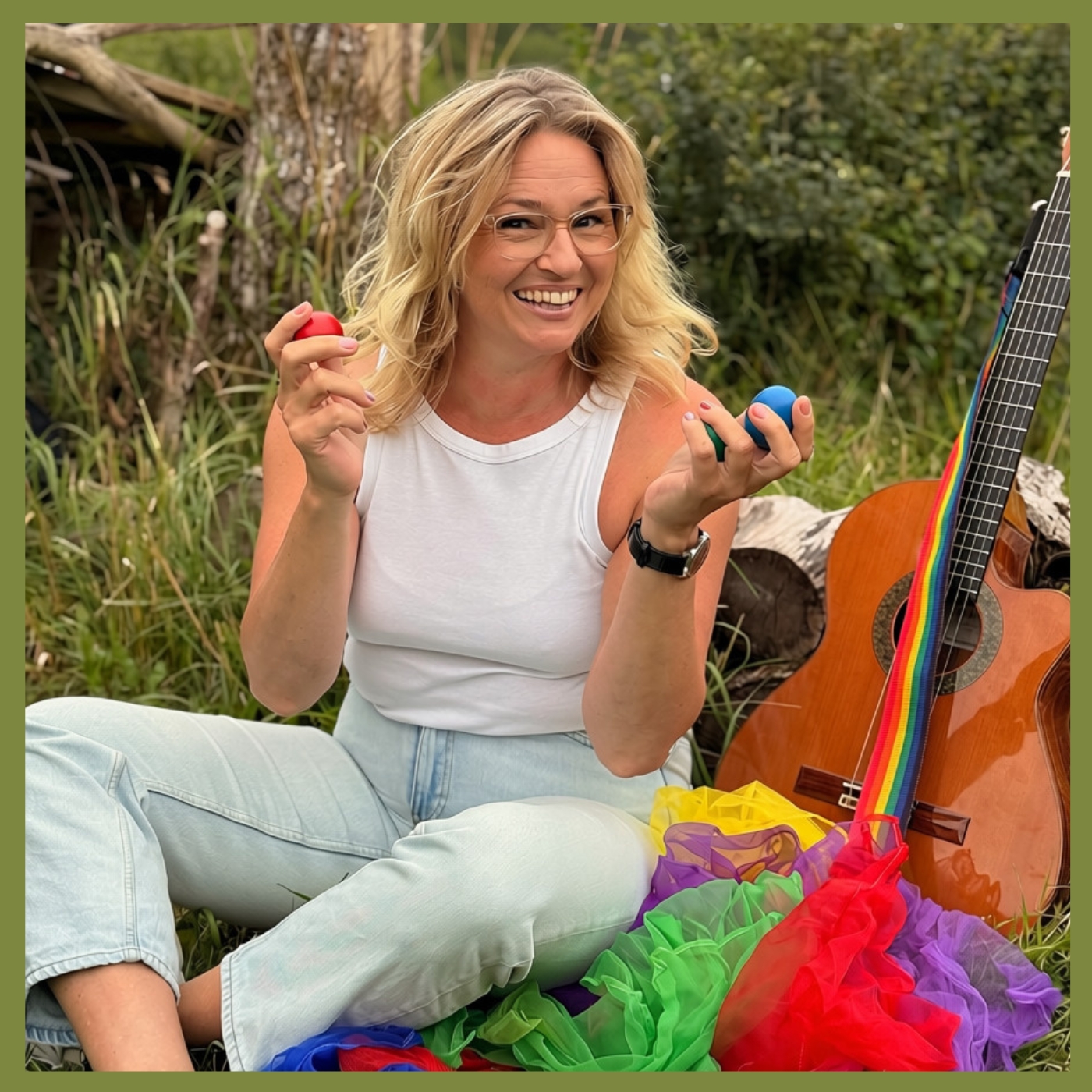 Rytmika sitter på gräset med rytmägg i händerna. Bredvid står en gitarr och färgglada sjalar ligger i gräset.