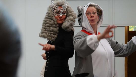 Två utklädda kvinnor dirigerar. Till vänster en kvinna utklädd likt Mozart. Till höger en kvinna utklädd till kattdjur.