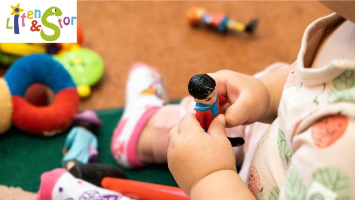 Närbild från sidan på ett litet barn som håller en leksaksfigur i händerna.