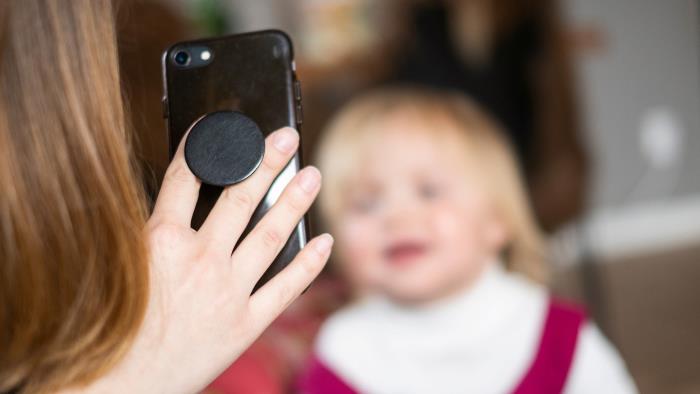 En kvinna filmar ett barn med mobilkamera. 