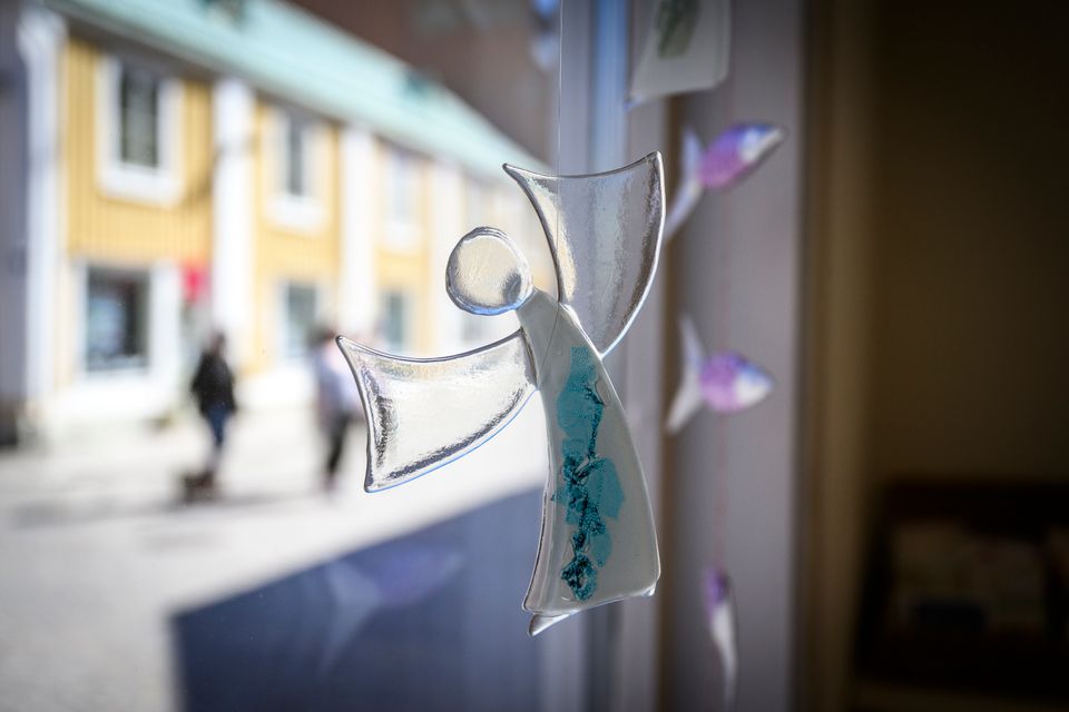 Skulptur i glas formad som en ängel som hänger i ett fönster