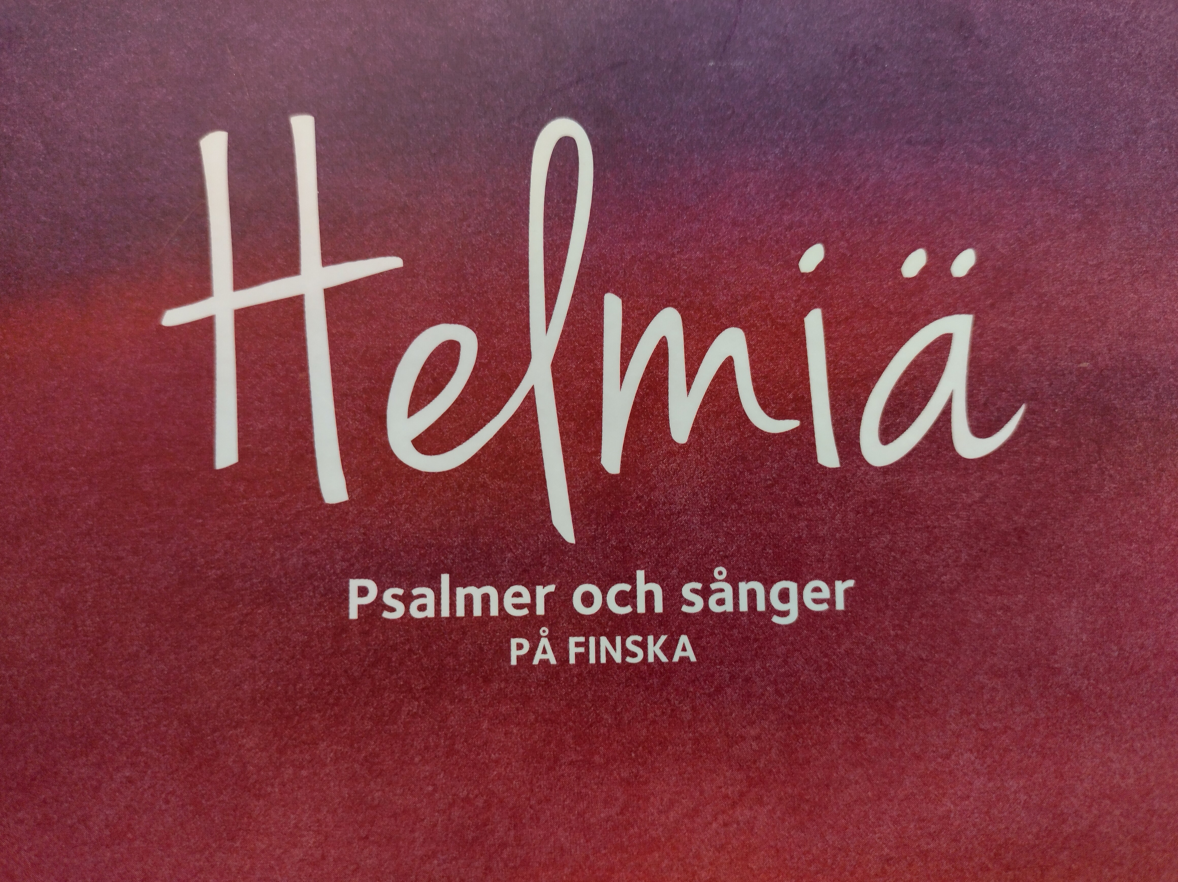 Röd bildbotten med texten Helmiä